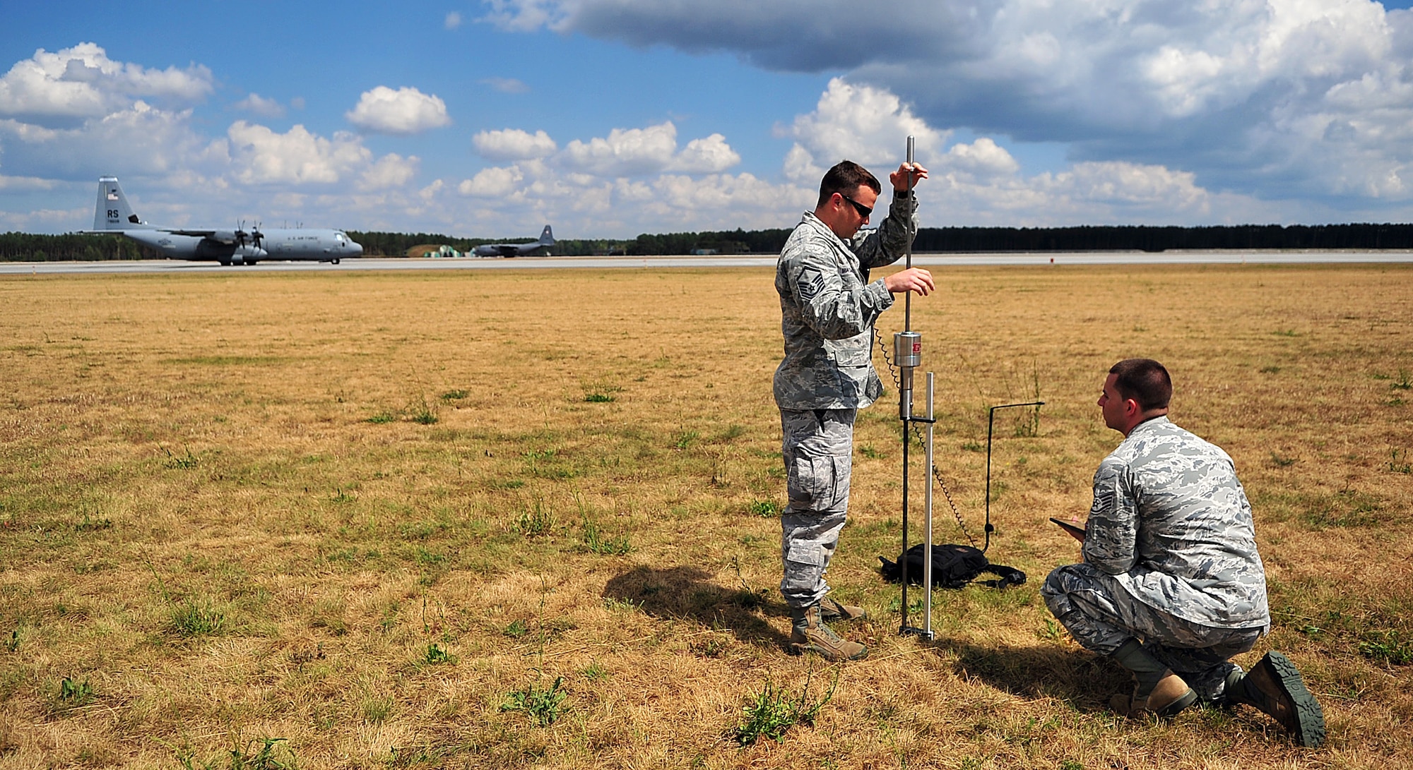 Master Sgt. Stanley MacDonald, 435th Aircraft Maintenance Squadron air traffic controller, and Staff Sgt. Brock Neel, 435th AMS engineer, survey an area for training with a dynamic cone penetrometer at Powidz Air Base, Poland, July 11, 2014. The measurement from the DCP is one of the steps in determining if an airfield is safe for an aircraft landing. The Airmen from the 435th AMS conducted grass landing zone training to accomplish C-130J Super Hercules pilots training requirements. (U.S. Air Force photo by Senior Airman Christine Griffiths/Released)