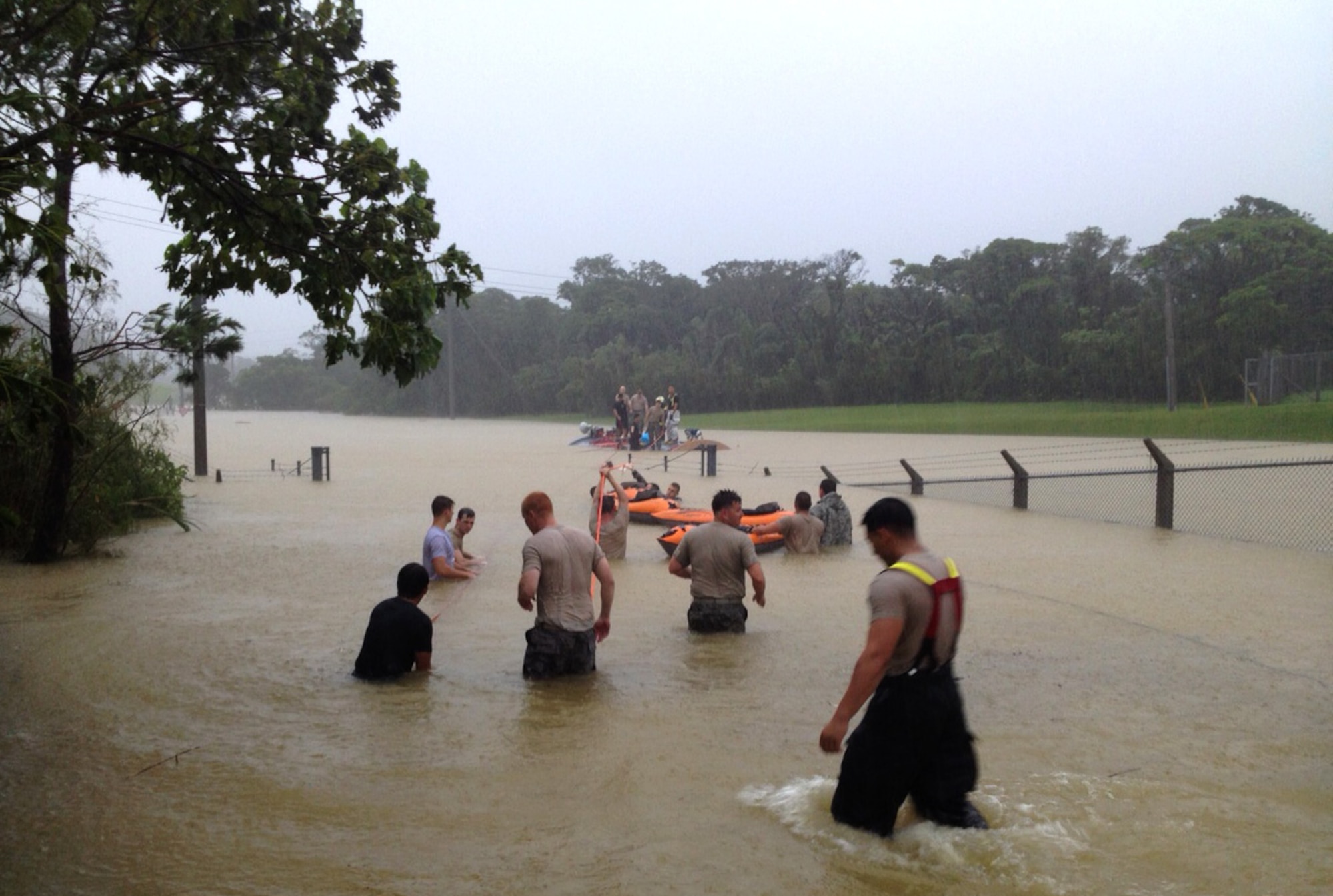 First responders work as a team to rescue two U.S. Air Force Airmen trapped inside a flooded guard shack on Kadena Air Base, Japan, July 9, 2014. The responders were able to successfully cut a hole in the guard shack and free the Airmen by using tools such as sledge hammers, axes and k-12 fire rescue saws. (Courtesy photo)