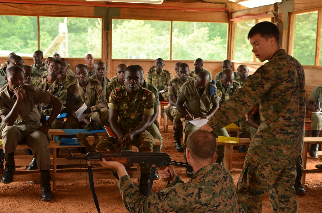 Lance Cpl. Mickey Anderson (standing) and Lance Cpl. Fletcher McQuire (sitting), Marines with Special-Purpose Marine Air-Ground Task Force Africa 14, discuss the fundamentals of marksmanship with members of a task force in Gabon, June 8, 2014. A team of 15 Marines and sailors trained with their Gabonese counterparts from the Agence Nationale des Parcs Nationaux and the Gabonese military and Gendarmerie to demonstrate tactics that could then be applied to combat all types of illicit activities, to include narcotics trafficking.
