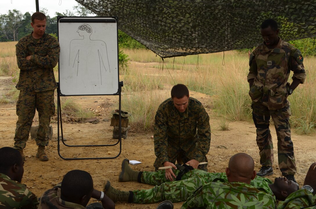 Lance Cpl. Fletcher McGuire (left) and Petty Officer 3rd Class Vance Hickling (kneeling), members of Special-Purpose Marine Air-Ground Task Force Africa 14, discuss applying tourniquets during a combat life-saving class with members of a task force in Gabon, June 9, 2014. A team of 15 Marines and sailors trained with their Gabonese counterparts from the Agence Nationale des Parcs Nationaux and the Gabonese military and Gendarmerie to demonstrate tactics that could then be applied to combat all types of illicit activities, to include narcotics trafficking.