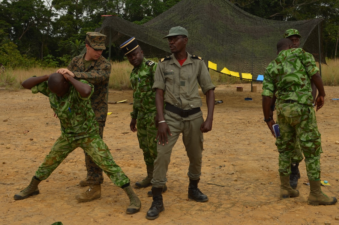Lance Cpl. Mickey Anderson, a Marine with Special-Purpose Marine Air-Ground Task Force Africa 14, demonstrates detainee handling with members of a task force in Gabon, June 10, 2014. A team of 15 Marines and sailors trained with their Gabonese counterparts from the Agence Nationale des Parcs Nationaux and the Gabonese military and Gendarmerie to demonstrate tactics that could then be applied to combat all types of illicit activities, to include narcotics trafficking.