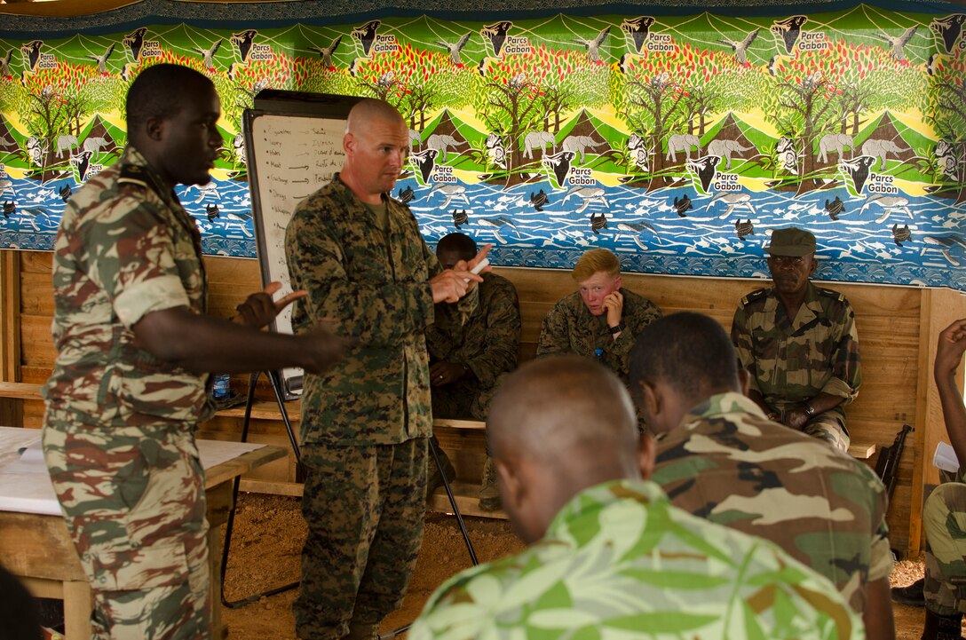 Captain Peter Driscoll, the team leader for a theater security cooperation team with Special-Purpose Marine Air-Ground Task Force Africa 14, discusses tactical site exploitation with members of a task force in Gabon, June 13, 2014. A team of 15 Marines and sailors trained with their Gabonese counterparts from the Agence Nationale des Parcs Nationaux and the Gabonese military and Gendarmerie to demonstrate tactics that could then be applied to combat all types of illicit activities, to include narcotics trafficking.