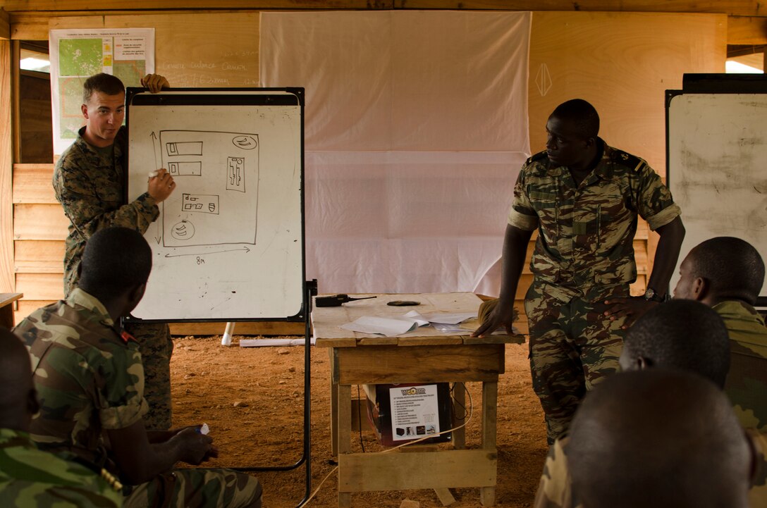 Lance Cpl. Fletcher McQuire, a Marine with Special-Purpose Marine Air-Ground Task Force Africa 14, discusses tactical site exploitation with members of a task force in Gabon, June 13, 2014. A team of 15 Marines and sailors trained with their Gabonese counterparts from the Agence Nationale des Parcs Nationaux and the Gabonese military and Gendarmerie to demonstrate tactics that could then be applied to combat all types of illicit activities, to include narcotics trafficking.