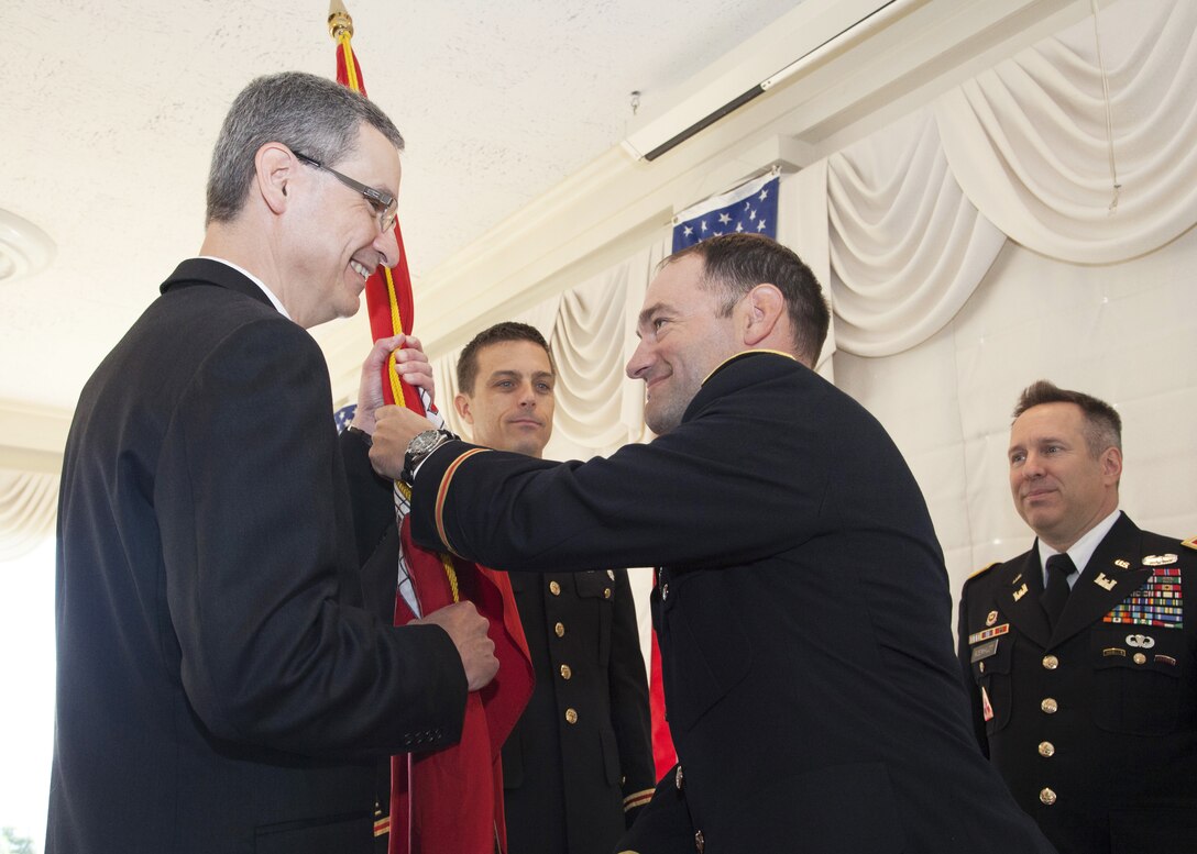 Having assumed command Lt. Col. Michael L. Sellers passes the colors to Scott Thieme, Detroit District deputy district engineer for project management, during the change of command ceremony, July 10, 2014.