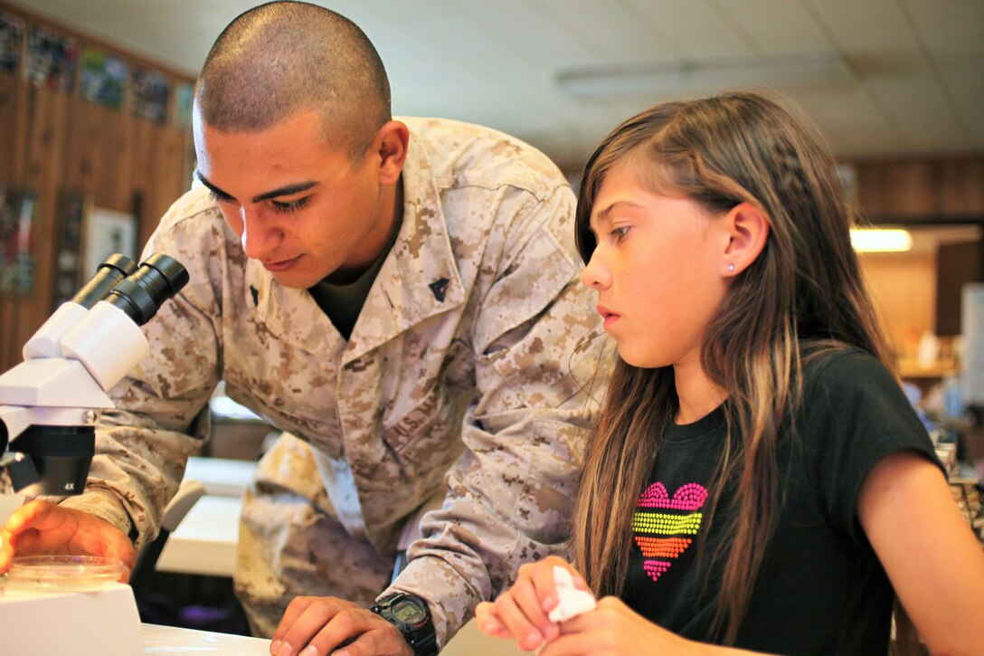 OLD HARBOR, Alaska - Cpl. Luis Ibarra, an electrical equipment repair technician with Marine Wing Support Squadron (MWSS) 473, observes a Bull Dog Fish through a microscope, with Angel Christiansen, a middle school student of Old Harbor, Alaska, July 15.  Reserve Marines attended a biology lab presented by Dr. Switgard Duesterloh, a marine biologist from Kodiak College, Alaska. Reserve Marines participating in Innovative Readiness Training Old Harbor, worked with the students during their liberty period. (U.S. Marine Corps photo by Cpl. David Waite)