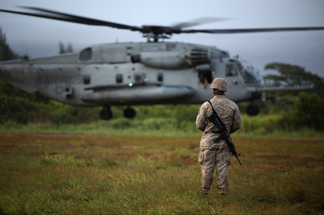 KAHUKU TRAINING AREA, Hawaii - A Marine with India Company, 3rd Battalion, 3rd Marine Regiment, waits as a CH53E Super Stallion helicopter flies away after dropping off  a resupply of water and food to the Marines at Kahuku Training Area during Rim of the Pacific (RIMPAC) Exercise 2014, July 13. The Marine Corps tested a sea-based concept during the operation, meaning supplies and logistics came from USS Peleliu off shore from KTA. Twenty-two nations, more than 40 ships and submarines, about 200 aircraft and 25,000 personnel are participating in RIMPAC from June 26 to Aug. 1 in and around the Hawaiian Islands and Southern California. The world's largest international maritime exercise, RIMPAC provides a unique training opportunity that helps participants foster and sustain the cooperative relationships that are critical to ensuring the safety of sea lanes and security on the world's oceans. RIMPAC 2014 is the 24th exercise in the series that began in 1971. (U.S. Marine Corps photo by Sgt. Sarah Dietz/Released)