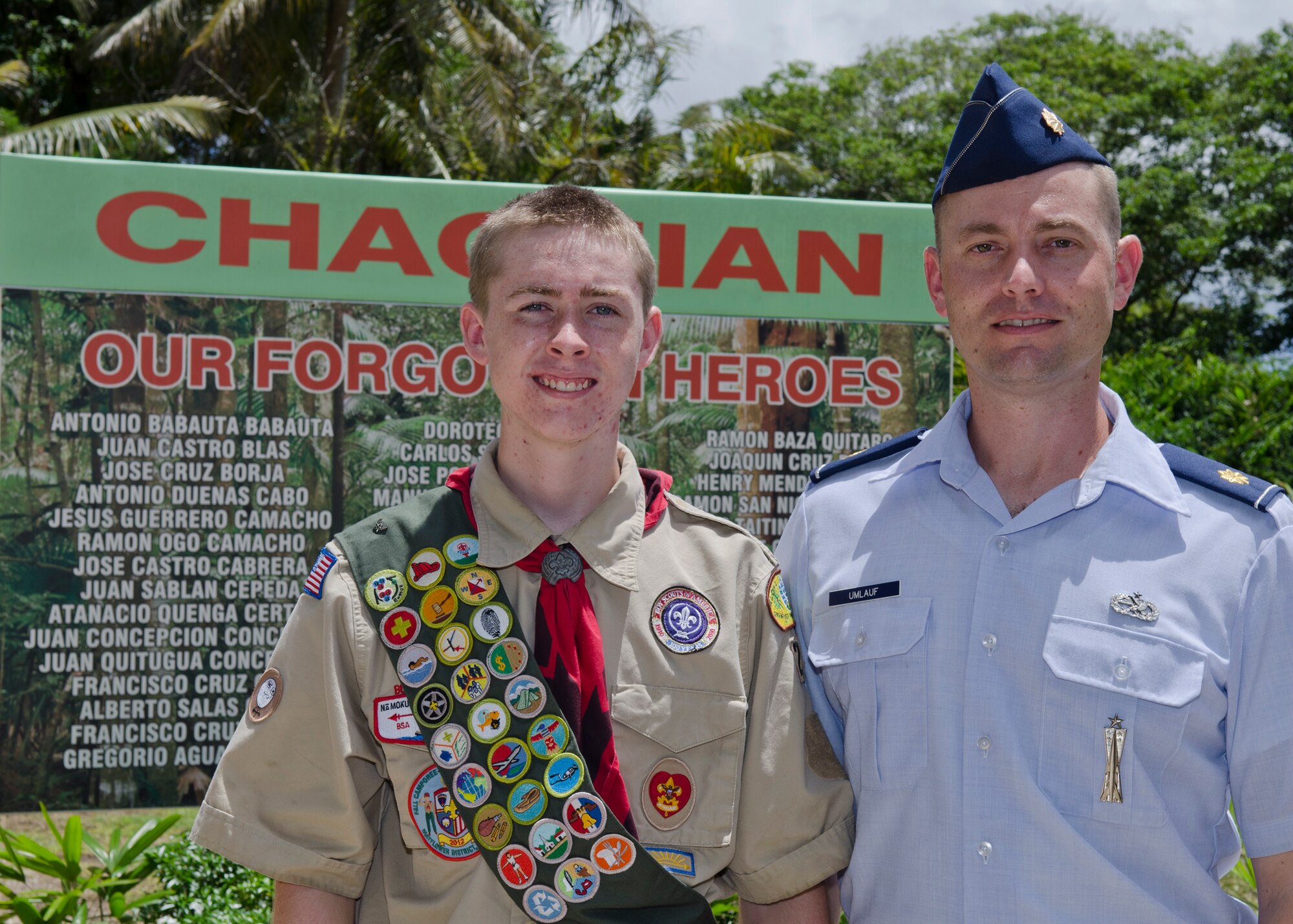 Troop 1420 Boy Scout Jackson Umlauf and his father Maj. Kurt Umlauf, 36th Munitions Squadron operations officer, stand in front of a memorial sign listing the names of the men lost in the Chagui'an Massacre in the village of Yigo, Guam, on July 14, 2014. The Umlaufs brought together the 36th MUNS and Boy Scouts of America Troop 1420 to update the forgotten memorial site. (U.S. Air Force photo by Senior Airman Katrina M. Brisbin/Released)