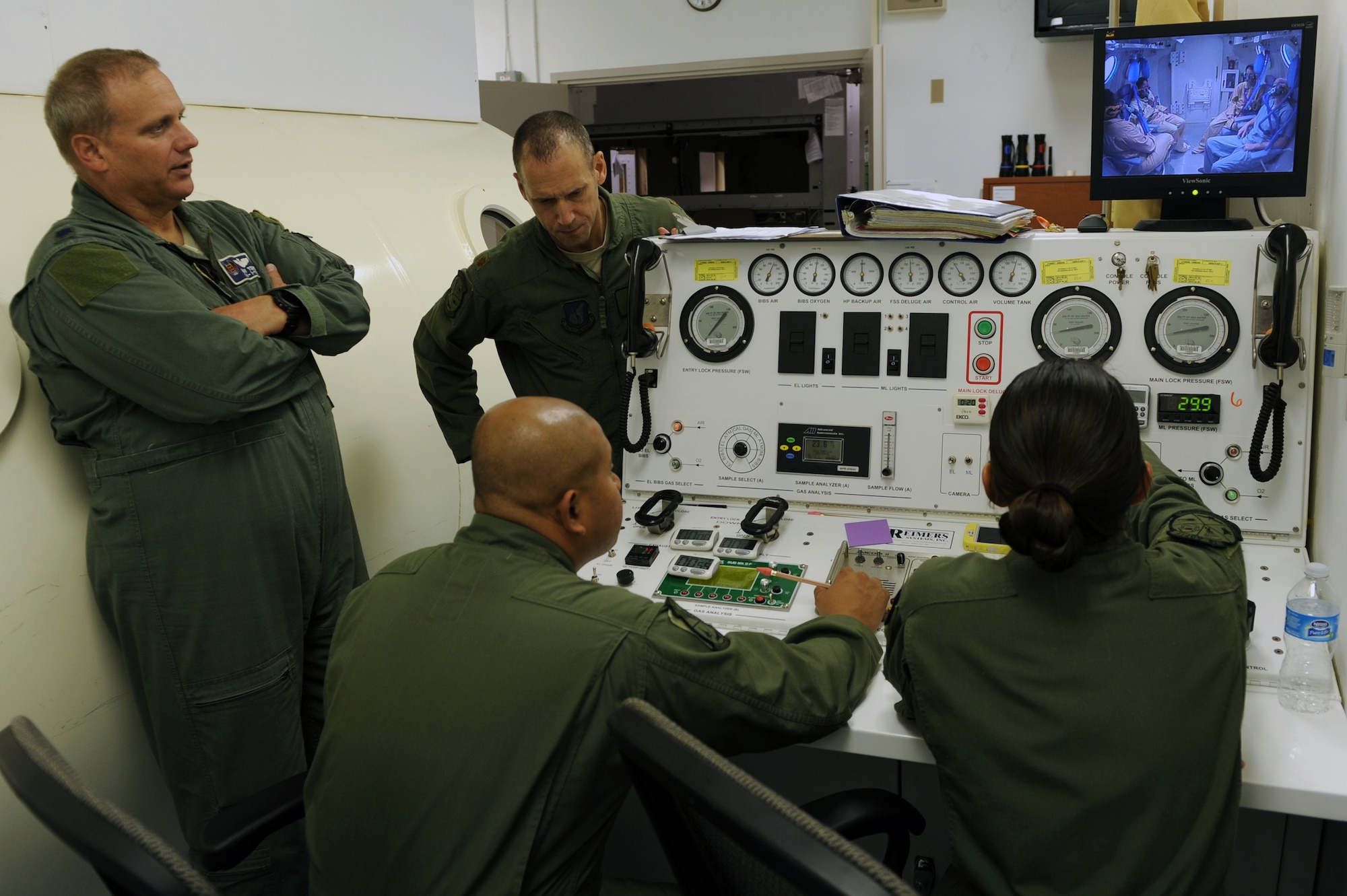 U.S. Air Force Lt. Col. Gary Toups (left), 44th Fighter Squadron undersea and hyperbaric medicine physician, Staff Sgt. Nazareth Oliver (front center), 18th Aerospace and Operational Physiological Training Flight NCO in charge of logistics and operations, Maj. Tim Stout (back center), 18th AOPT flight commander, and Staff Sgt. Cristina Valentin (right), 18th AOPT NCO in charge of administration and training, communicate with Airmen inside a hyperbaric chamber on Kadena Air Base, Japan, July 17, 2014. The Airmen inside the chamber felt the effects of pressure equal to that of being 160 feet below sea level. Since use of Kadena’s hyperbolic chamber has been discontinued due to budget and manning constraints, divers suffering from decompression injury will be treated off-base with assistance from Camp Foster Naval Hospital personnel. (U.S. Air Force photo by Airman 1st Class Zade C. Vadnais)