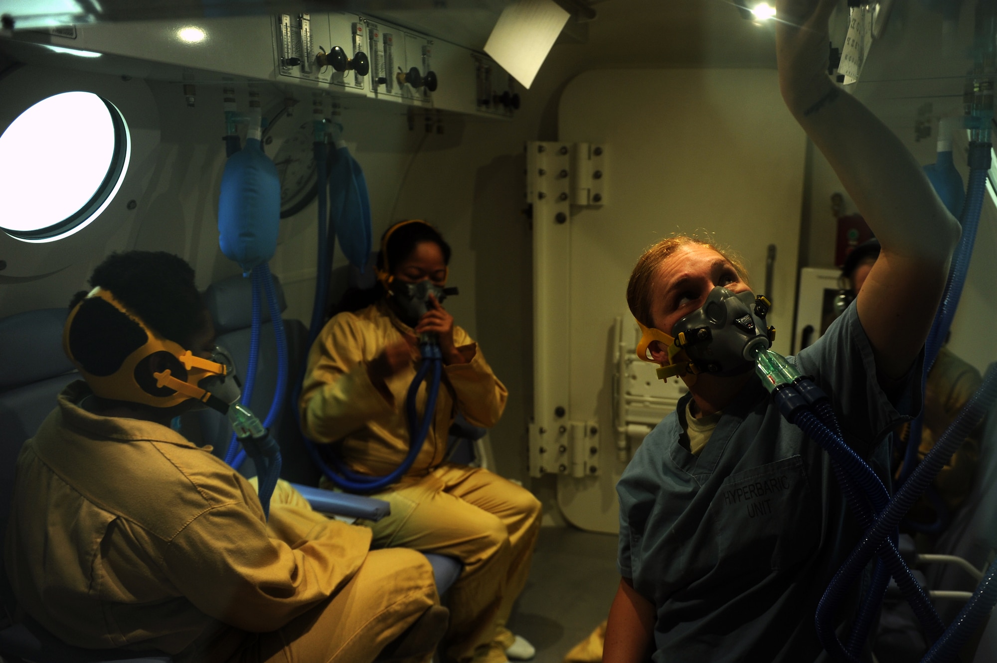 U.S. Air Force Tech. Sgt. Charrissa Smith, 18th Aerospace and Operational Physiological Training Flight chief, adjusts the level of oxygen flowing into her mask while inside a hyperbaric chamber on Kadena Air Base, Japan, July 17, 2014. Smith, Staff Sgt. Kimberly Weaver (left), 18th Aerospace Medicine Squadron independent duty medical technician, Tech. Sgt. Sabrina Torries (center), 18th Medical Operations Squadron ambulance services technician, and Staff Sgt. Sherenda Fausnaugh (not pictured), 18th MDOS independent duty medical technician, were the last Airmen to undergo pressure change in Kadena’s hyperbaric chamber. Use of the chamber has been discontinued due to budget and manning constraints. (U.S. Air Force photo by Airman 1st Class Zade C. Vadnais)
