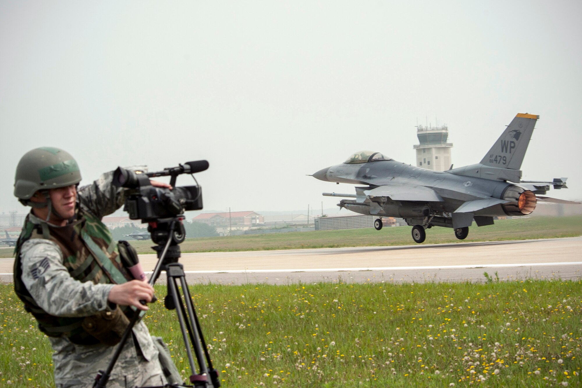 Staff Sgt. Jose Rodriguez, 8th Fighter Wing public affairs broadcasting NCOIC, documents an F-16 Fighting Falcon taking off during exercise Beverly Midnight 14-2 at Kunsan Air Base, Republic of Korea, July 16, 2014. The Operational Readiness Exercise assesses mission capabilities and ensures the Wolf Pack is in a constant state of readiness. (U.S. Air Force photo by Senior Airman Taylor Curry/Released) 
