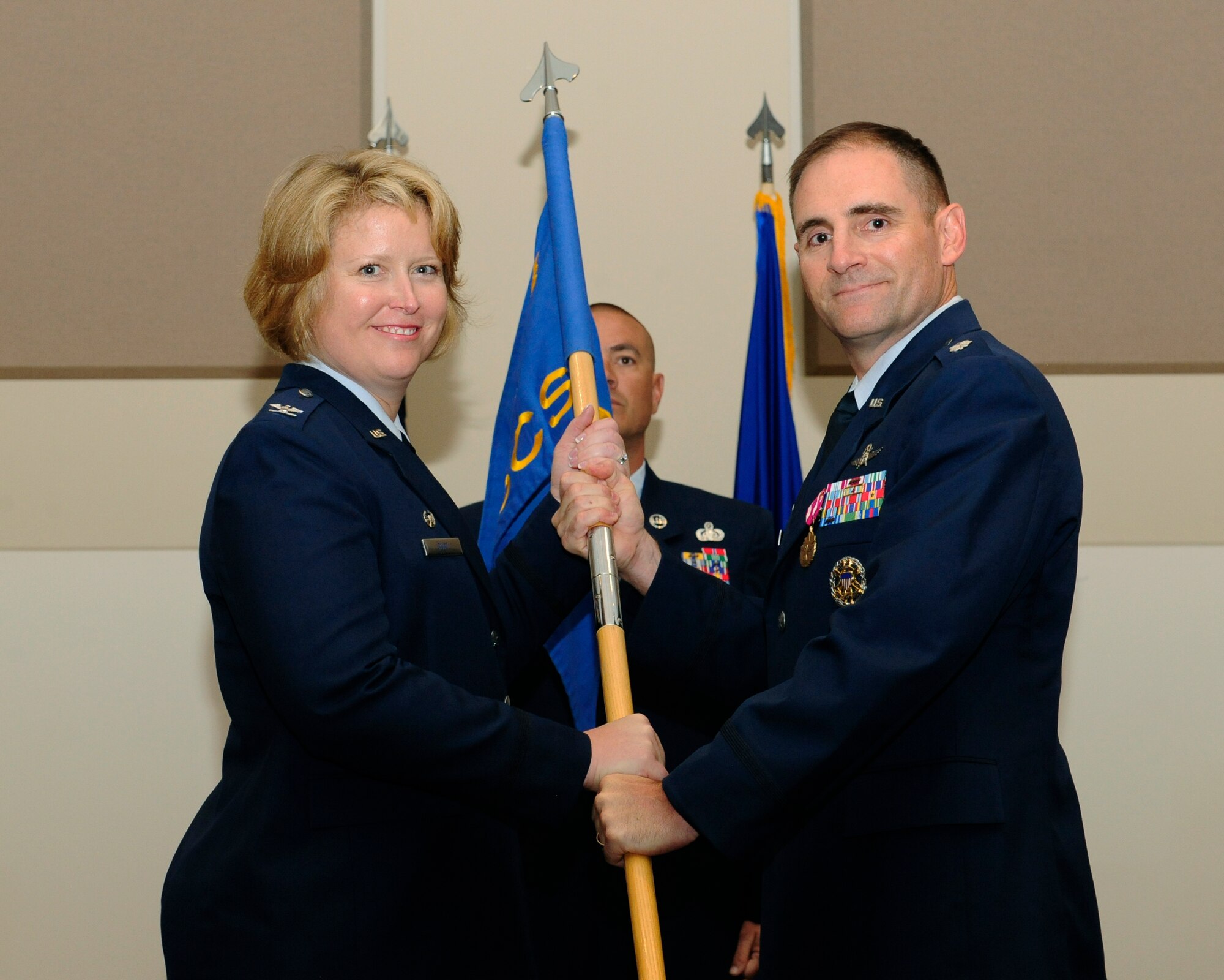 Lt. Col. Hew Wells, right, relinquishes his command of the 460th Space Communications Squadron to Col. DeAnna Burt, 460th Operations Group commander, during the 460th SCS Change of Command ceremony July 17, 2014, at the Leadership Development Center on Buckley Air Force Base, Colo. The event signaled Maj. Christopher Kennedy, 460th SCS commander, assuming command from Wells, who served as commander of the 460th SCS for two years. (U.S. Air Force photo by Airman 1st Class Samantha Saulsbury/Released)