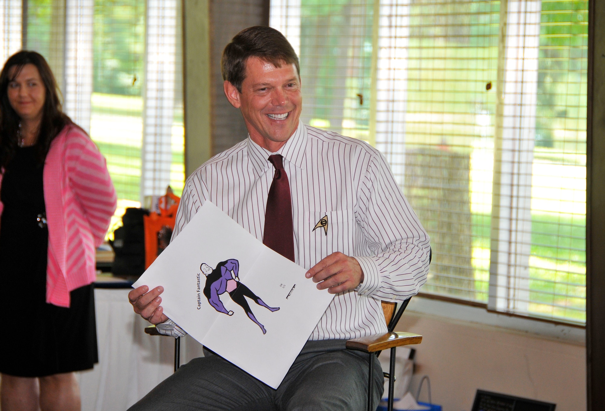 During his farewell luncheon held June 20, Dr. Doug Blake’s colleagues had the opportunity to share stories about their time working with him. Pictured is Blake holding up a sign with a character called “Captain Fantastic” he received from Clark Brandon. Brandon said he had the idea for this character because Blake could sometimes be seen doodling pictures and flowcharts during meetings. Brandon also shared that he even came up with the tune “Do You Want to Build a Flowchart?” to poke fun at Blake’s doodling habit. (Photo by Jacqueline Cowan)