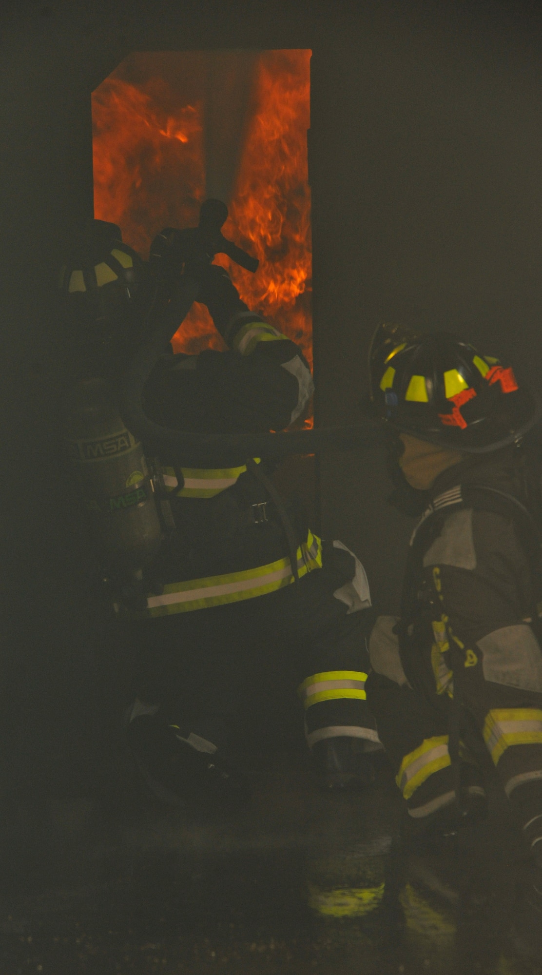 Firefighters from the 319th Civil Engineer Squadron put out a simulated bedroom fire during a training exercise on July 15, 2014, on Grand Forks Air Force Base, N.D. The annual fire training consists of extinguishing a simulated house fire while using proper fire hose techniques. (U.S. Air Force photo/Senior Airman Xavier Navarro)