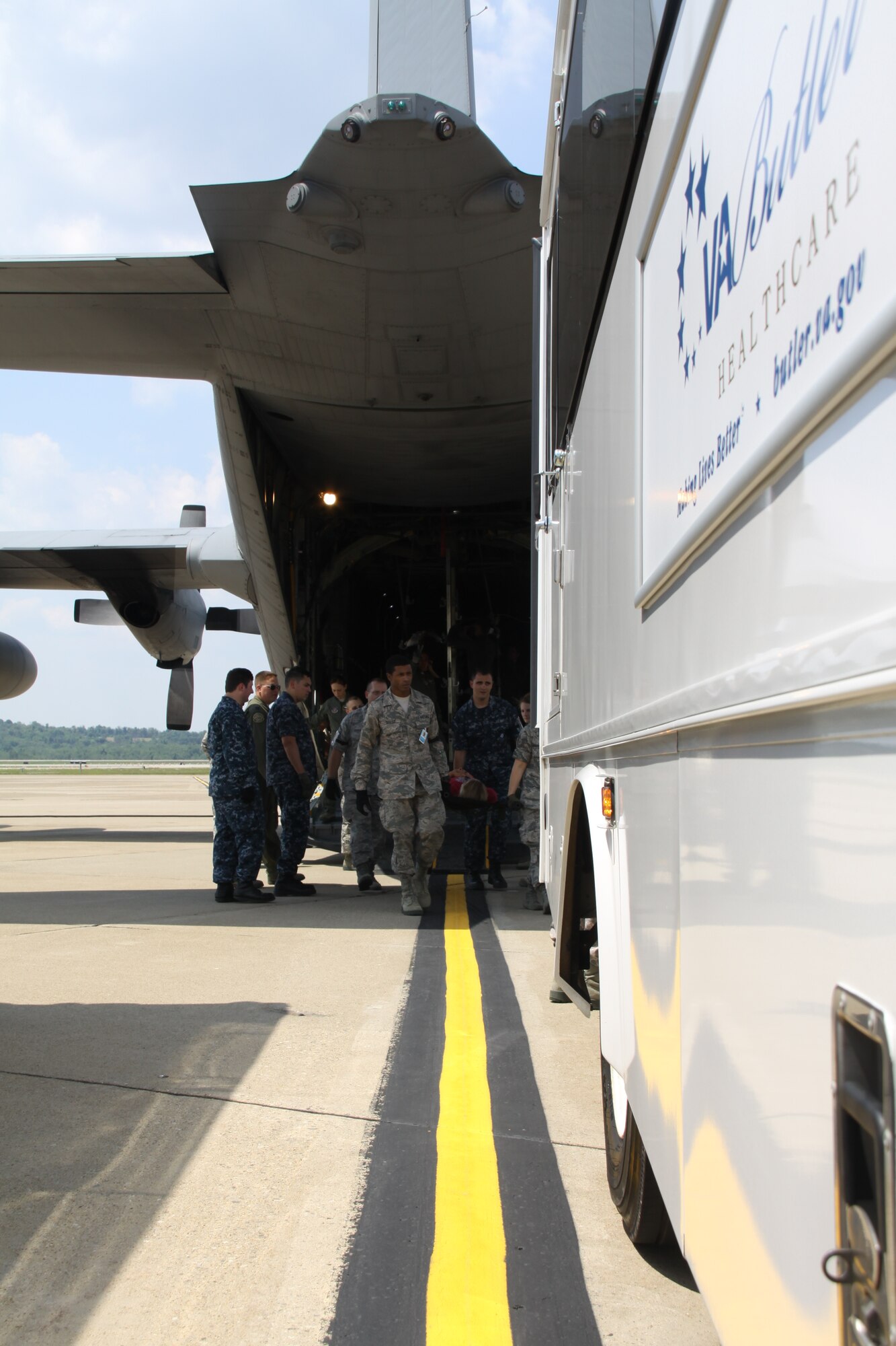 Air Force and Navy members work together to transfer simulated victims from a C-130 Hercules aircraft to a Veterans Affairs medical center bus, during a National Disaster Medical System Exercise at the Pittsburgh International Airport Air Reserve Station, July 12, 2014. (U.S. Air Force photo by Staff Sgt. Jonathan Hehnly)