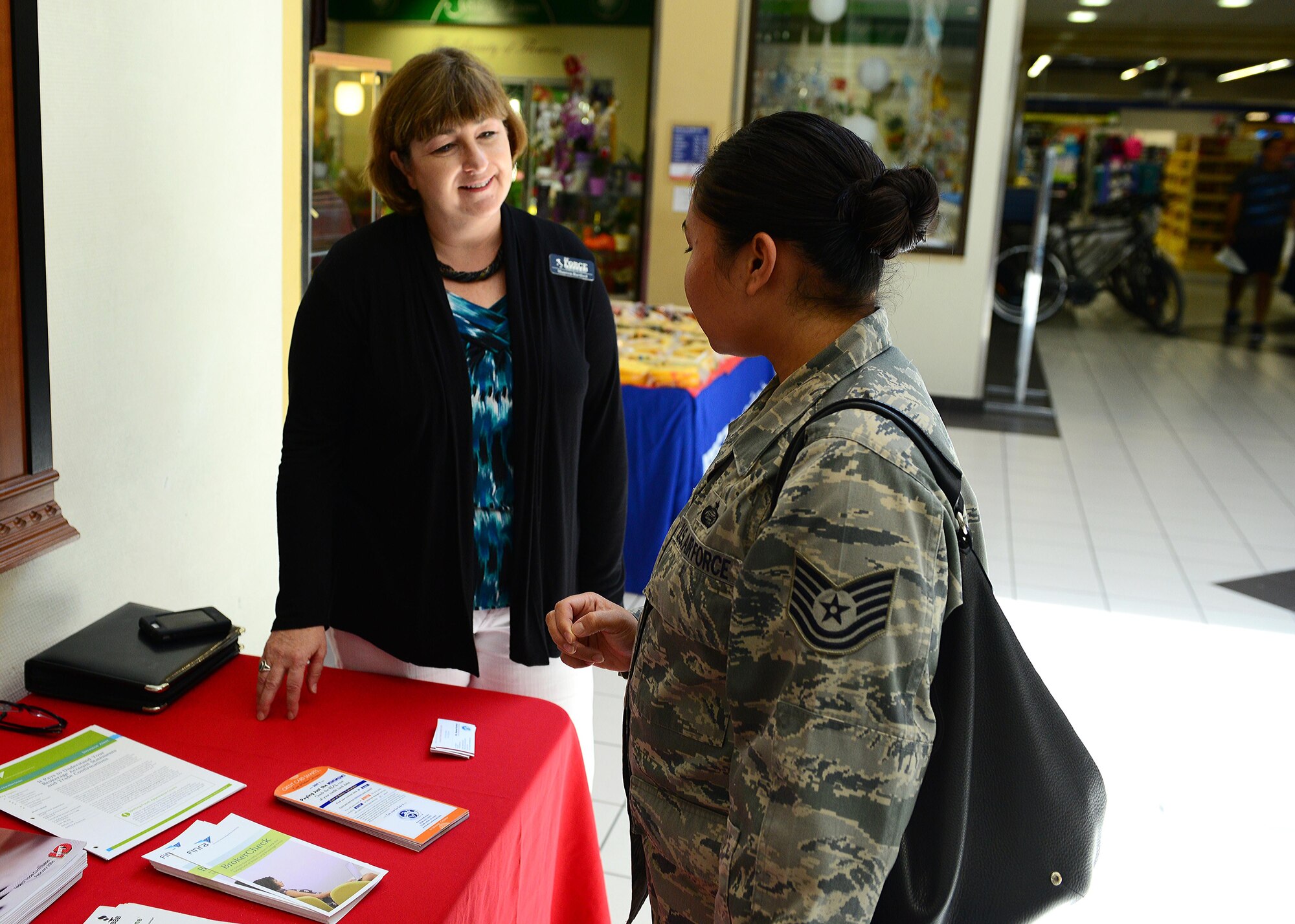 Maureen Hartford, 31st Force Support Squadron community readiness consultant, talks to Tech. Sgt. Grace Barce, 31st FSS NCO in charge of career development, during the Military Protection Day booth at the Exchange, July 16, 2014, at Aviano Air Base, Italy. The year-long campaign helps empower service members with the tools and information to be properly informed about their financial future.  (U.S. Air Force photo/Senior Airman Matthew Lotz)