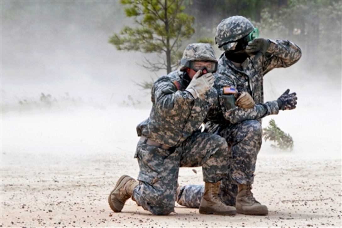 Army Sgt. Darryl Wright, right, and Army Pfc. Brandon Verano wait for the dust to settle after hooking up a water buffalo to a UH-60 Black Hawk helicopter to practice slingload operations on Fort Jackson, S.C., July 13, 2014. Wright and Verano are guardsmen assigned to the South Carolina National Guard's 351st Aviation Support Battalion. 