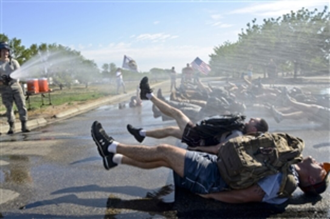 Airmen use a fire hose to spray members participating in the Goruck Light Challenge on Mountain Home Air Force Base, Idaho, July 12, 2014. The Idaho base is the first of 18 Air Force bases to test the Team Cohesion Challenge. The airmen are assigned to 366th Civil Engineering Squadron's fire department.  A key to the challenge is how quickly participants adapt to the obstacles, such as carrying a 250-pound raft on their shoulders, while performing as a synergized group.