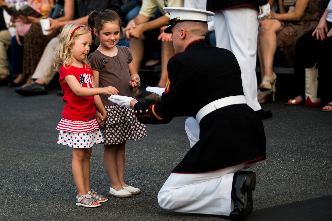 Sgt. Chase Mullens, Marine Barracks Washington, D.C., crowd educator, gives dress blues buttons to children prior to the start of a Friday Evening Parade at the Barracks, July 11, 2014. (Official Marine Corps photo by Cpl. Dan Hosack/Released)