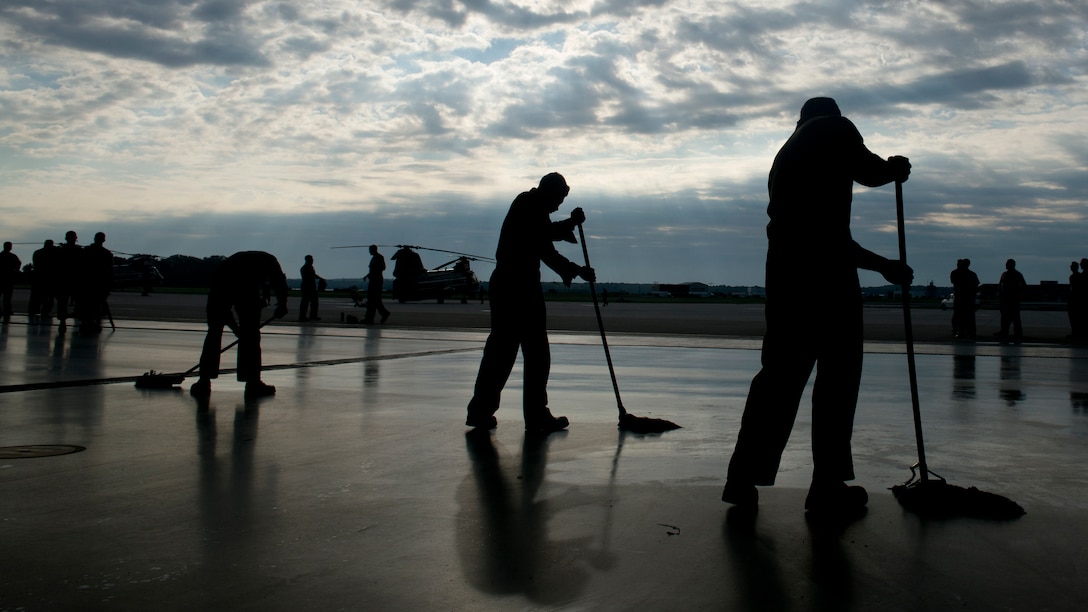 Marines with Marine Corps Helicopter Squadron One, Headquarters Marine Corps, swab the deck of their hangar on Marine Corps Air Facility Quantico to prepare for a breakfast they hosted to commemorate the last flight of the CH-46E Sea Knights from their Squadron July 16, 2014. (U.S. Marine Corps photo by Cpl. Jose D. Lujano/Released)