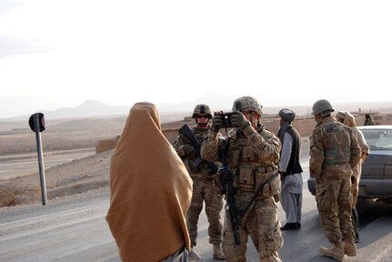 North Carolina Army National Guard Sgt. Thomas Parker enrolls an Afghani local national into a hand-held interagency identity detection equipment.