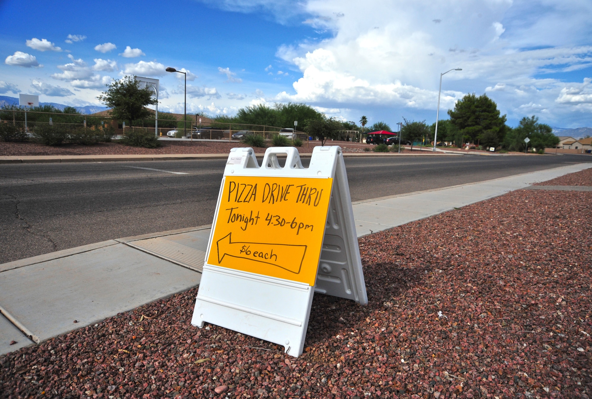 A sign reminding base residents of Drive-Thru Pizza Night is posted across the street from Soaring Heights Communities Welcome Home Center at Davis-Monthan Air Force Base, Ariz., July 16, 2014.  The event, hosted by Soaring Heights, offers a special price for large pepperoni or cheese pizza to anyone with access to the base.  (U.S. Air Force Photo by Airman 1st Class Chris Massey/Released) 