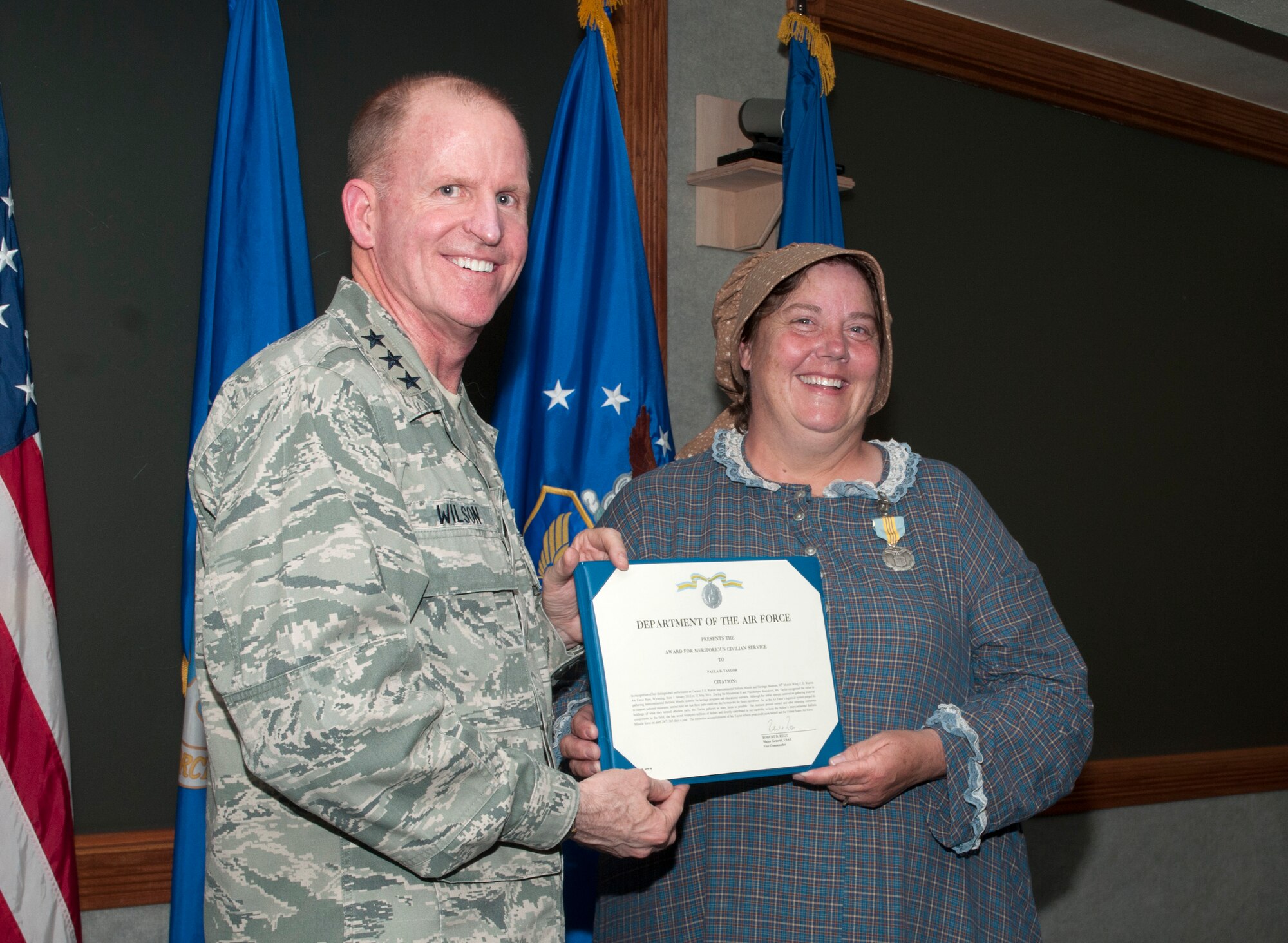 Lt. Gen. Stephen Wilson, Commander, Air Force Global Strike Command, Barksdale Air Force Base, La., presents the Meritorious Civilian Service Award to Paula Taylor, Warren ICBM & Heritage Museum director, July 18, 2014, at F.E. Warren Air Force Base. Taylor was presented the award for her continuous support of the ICBM mission. She helped reintroduce parts determined obsolete by the Air Force Logistical System back into active service saving the Air Force, Department of Defense and taxpayers millions of dollars.