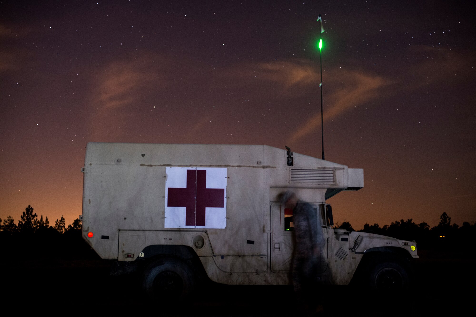 A Soldier from the 82nd Airborne Division walks past a High Mobility Multi-Purpose Wheeled Vehicle Ambulance during training on Camp Rudder, Fla., July 16, 2014. The 1st Special Operations Support Squadron HAVE-ACE hosted a joint operation exercise that allows military members to train how they fight. (U.S. Air Force photo/Senior Airman Christopher Callaway)