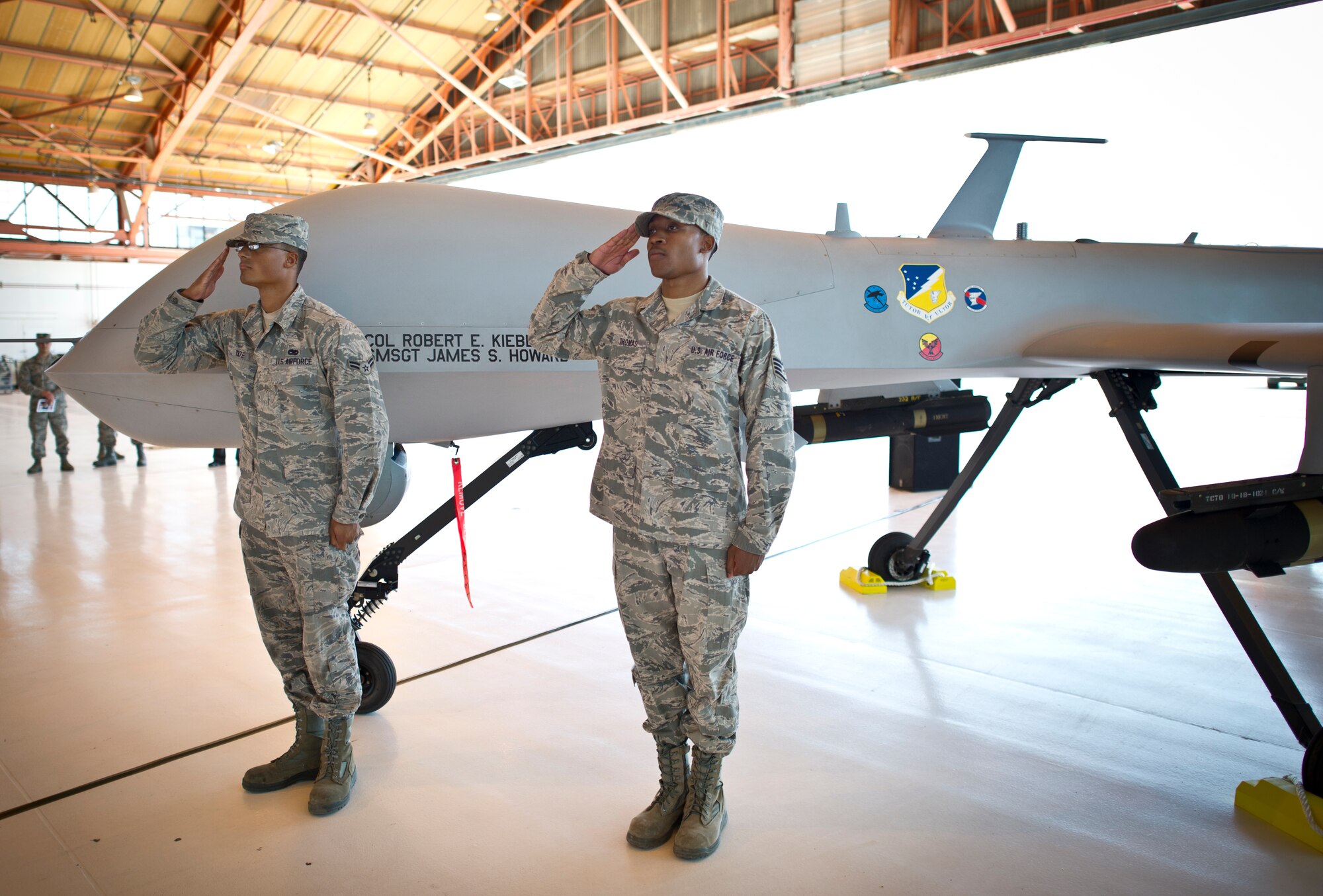 Airman 1st Class Aaron Tate and Staff Sgt. Terrelle Thomas, both from the 49th Aircraft Maintenance Squadron salute Col. Robert Kiebler, 49th Wing commander, after unveiling his name on an MQ-1 Predator at Holloman Air Force Base, N.M., July 18. An assumption or change of command is a military tradition that represents a formal transfer of authority and responsibility for a unit from one commanding officer to another. (U.S. Air Force photo by Staff Sgt. Stacy Moless / Released)
