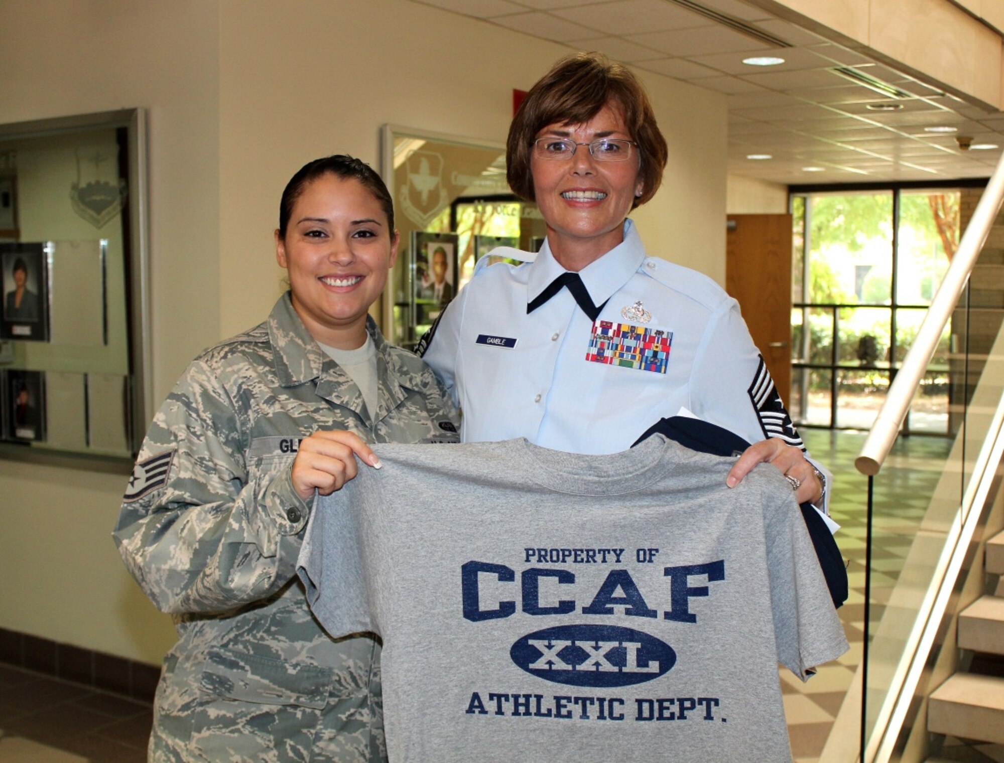 Staff Sgt. Vanessa Glenn, Community College of the Air Force, and Chief Master Sgt. Victoria Gamble, Air Mobility Command command chief, display their Community College of the Air Force T-shirt at Ryan Hall inside the CCAF Administrative Center at Maxwell Air Force Base, Alabama. The CCAF serves more than 305,000 active, Guard, and Reserve enlisted personnel, making it the world’s largest community college system. (U.S. Air Force photo/Staff Sgt. Paul Davis) 