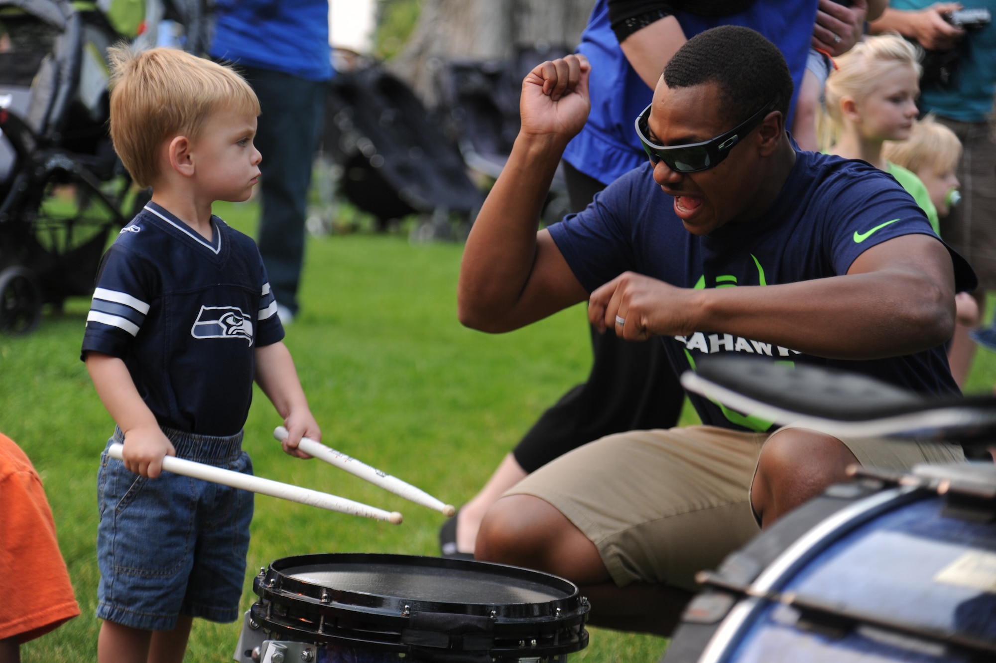 A Blue Thunder Band member teaches a kid how to play the drums during the ‘Heros of 12’ Military Appreciation Tour at Fairchild Air Force Base, Washington, July 17, 2014. The purpose of the tour was to show appreciation for the U.S. Military and their families, for their sacrifices, dedication and service to our country. (U.S. Air Force photo by Airman 1st Class Janelle Patiño/Released)