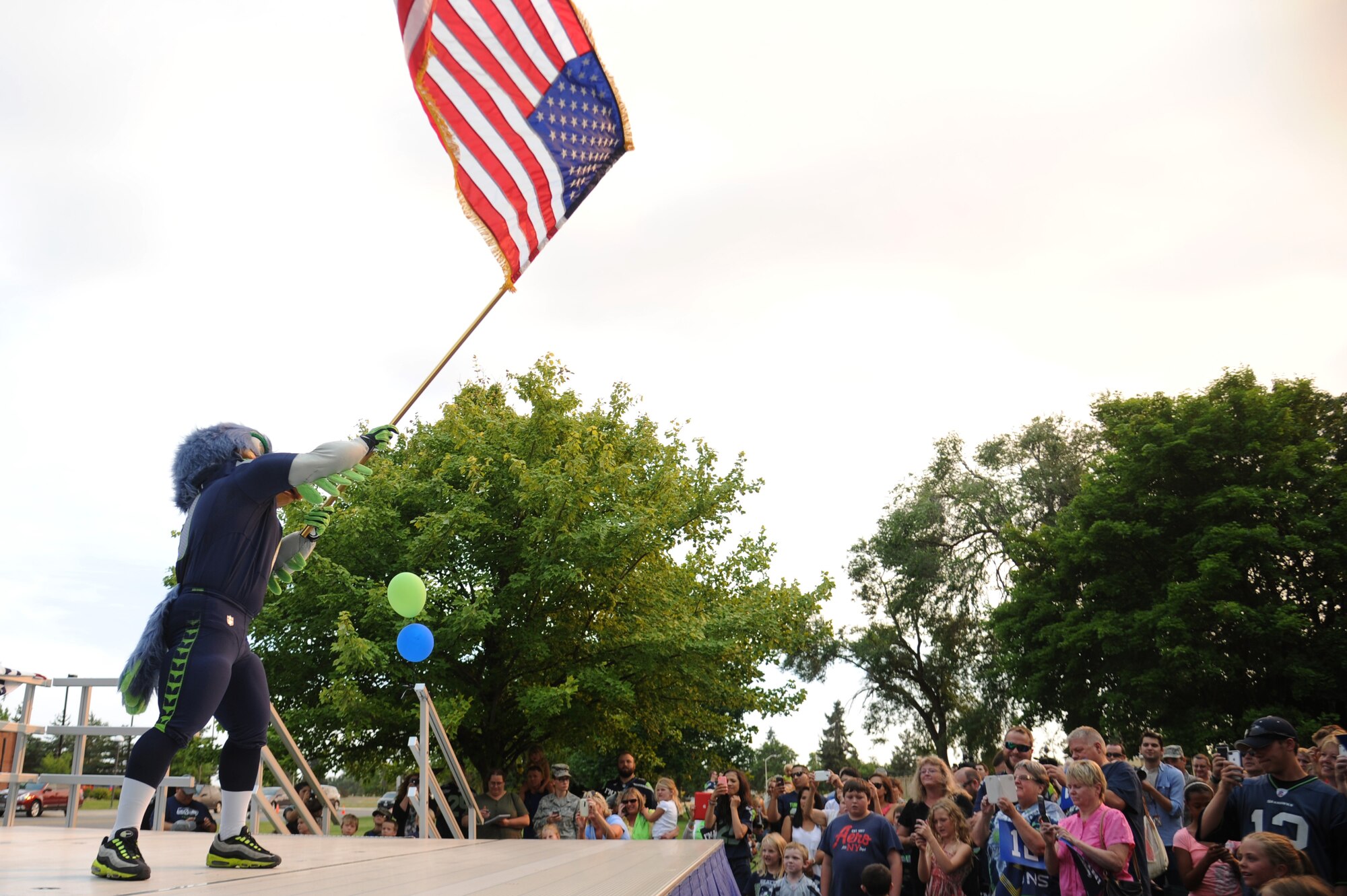 Blitz the mascot waves the flag during the ‘Heros of 12’ Military Appreciation Tour at Fairchild Air Force Base, Washington, July 17, 2014. The tour consists of Seahawk players, Seagals cheerleaders, the Blue Thunder Band, Taima the Hawk with falconer David Knutson, Blitz the official team mascot and the Lomabardi trophy. (U.S. Air Force photo by Airman 1st Class Janelle Patiño/Released)