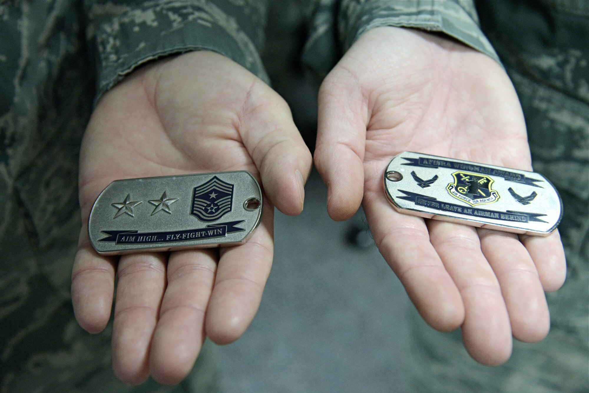 Tech. Sgts. Tyler Cresap and Clinton Kincade show both sides of the special Air Force Intelligence, Surveillance and Reconnaissance Agency Wingman coin they  were presented July 17 for responding to a retiree who suffered a seizure in the Nellis Air Force Base, Nevada, Exchange. (U.S. Air Force photo by SSgt. Jarrod Chavana)