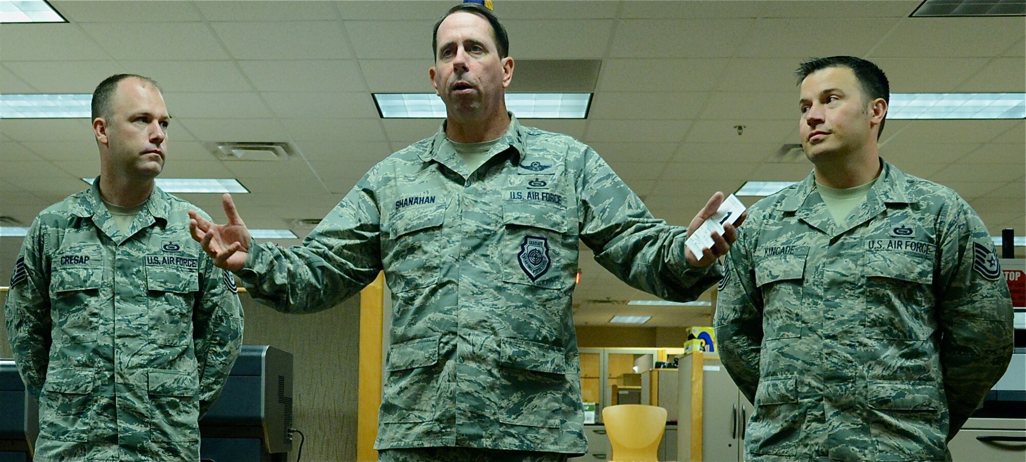 Maj. Gen. John Shanahan, Air Force Intelligence, Surveillance and Reconnaissance Agency commander addresses agency members prior to coining  Tech. Sgts. Tyler Cresap, left, and Clinton Kincade July 17 for responding to a retiree who suffered a seizure in the Nellis Air Force Base, Nevada, Exchange. (U.S. Air Force photo by SSgt. Jarrod Chavana)