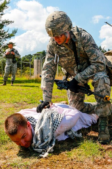 A 446th Security Forces Squadron Reservist from McChord Field, Washington is subdued by an airmen in training during an exercise scenario July 16, near Baumholder, Germany. The Reservist was pretending to be a refugee who found a way onto base so that he could search for food and water. The purpose of the training is to allow airmen to practice different scenarios they may face down range prior to deployment. (U.S. Air Force Reserve photo by Senior Airman Madelyn McCullough)