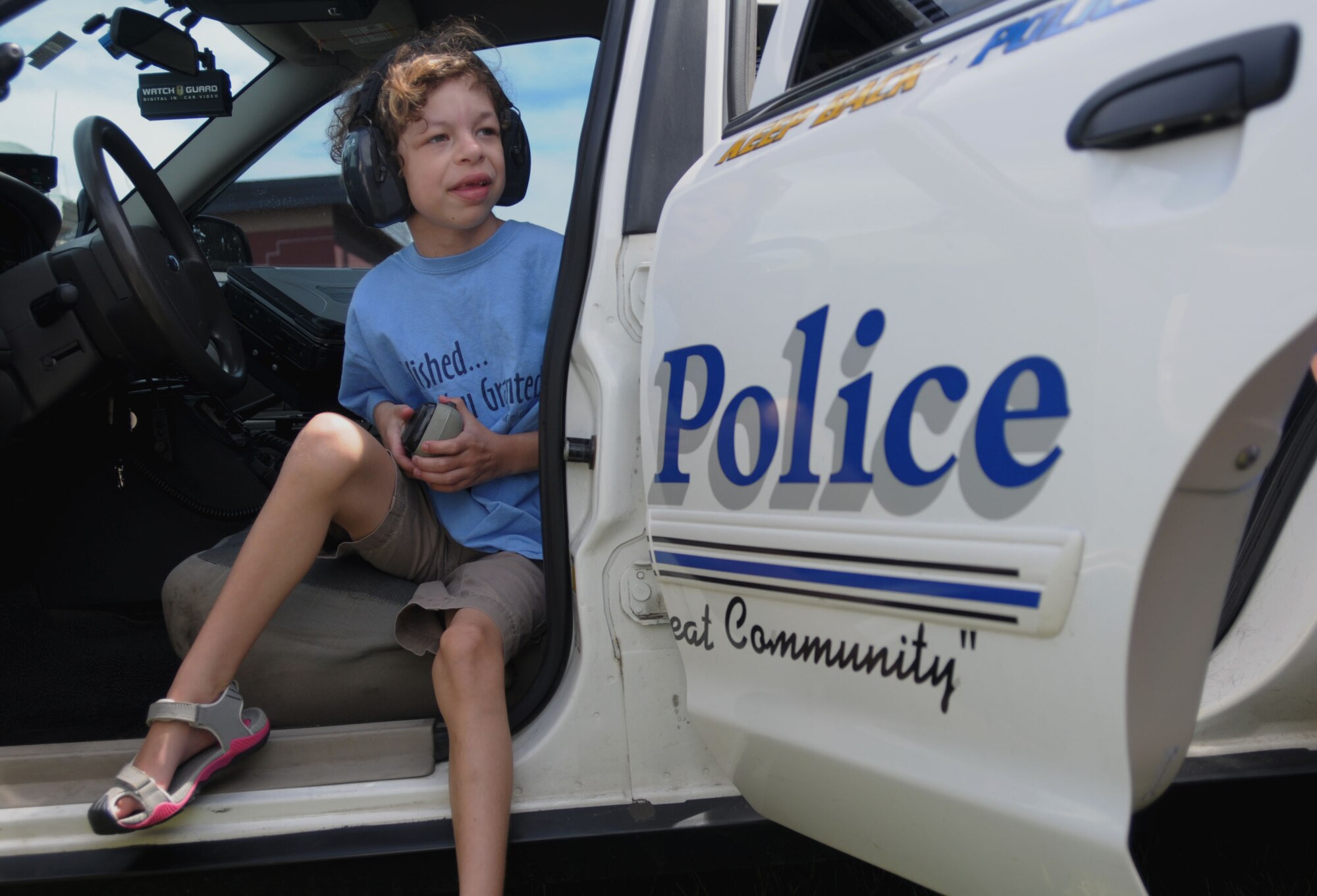 PEASE AIR NATIONAL GUARD BASE, N.H. -- Clare Rouillard experiences the inside of a police car after watching a demonstration from the Wells, Maine Police Department on how to operate the lights and speaker July 17. Eight children and their families were welcomed to Pease by Airmen who lined the sidewalk at the main gate, received demonstrations from the Dover Mounted Patrol and a Military Working Dog demonstration, enjoyed lunch at the Fire Department and toured the inside of a KC-135. (N.H. Air National Guard photo by Airman 1st Class Kayla McWalter/RELEASED)