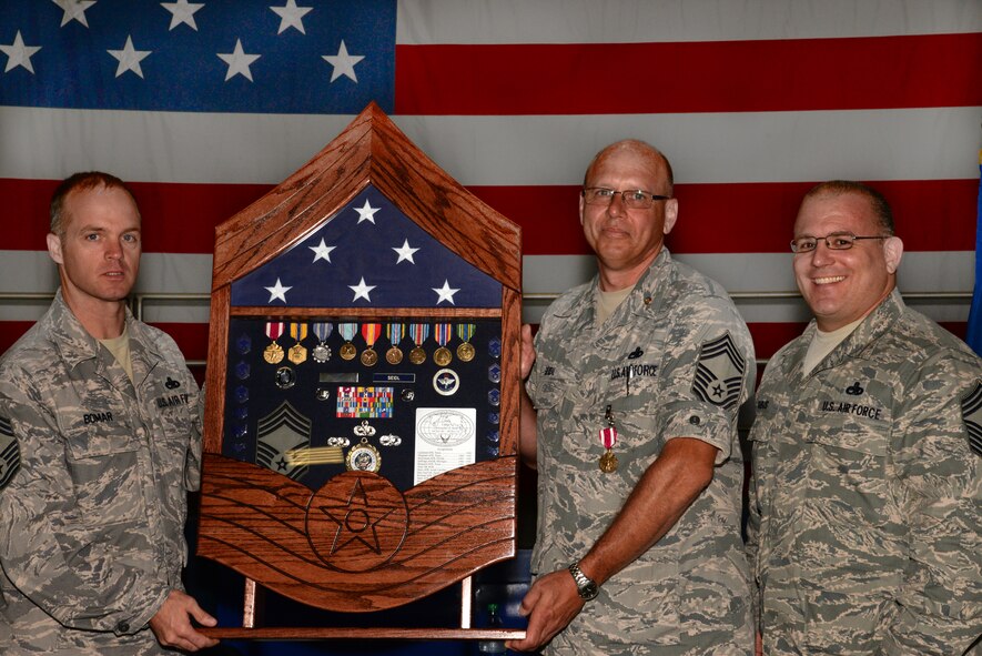 U.S. Air Force Chief Master Sgt. Christopher Seidl, 20th Maintenance Group superintendent (center), receives a shadow box during his retirement ceremony from Chief Master Sgts. Anthony Bomar, 20th MXG wing weapons manager (left), and Mark Sobus, 20th MXG quality assurance superintendent (right), at Shaw Air Force Base, S.C., July 18, 2014. Seidl has spent approximately 30 years in the Air Force; more than 10 of those years were with the 20th Fighter Wing at Shaw spanning three different assignments. (U.S. Air Force photo by Airman 1st Class Jonathan Bass/Released)