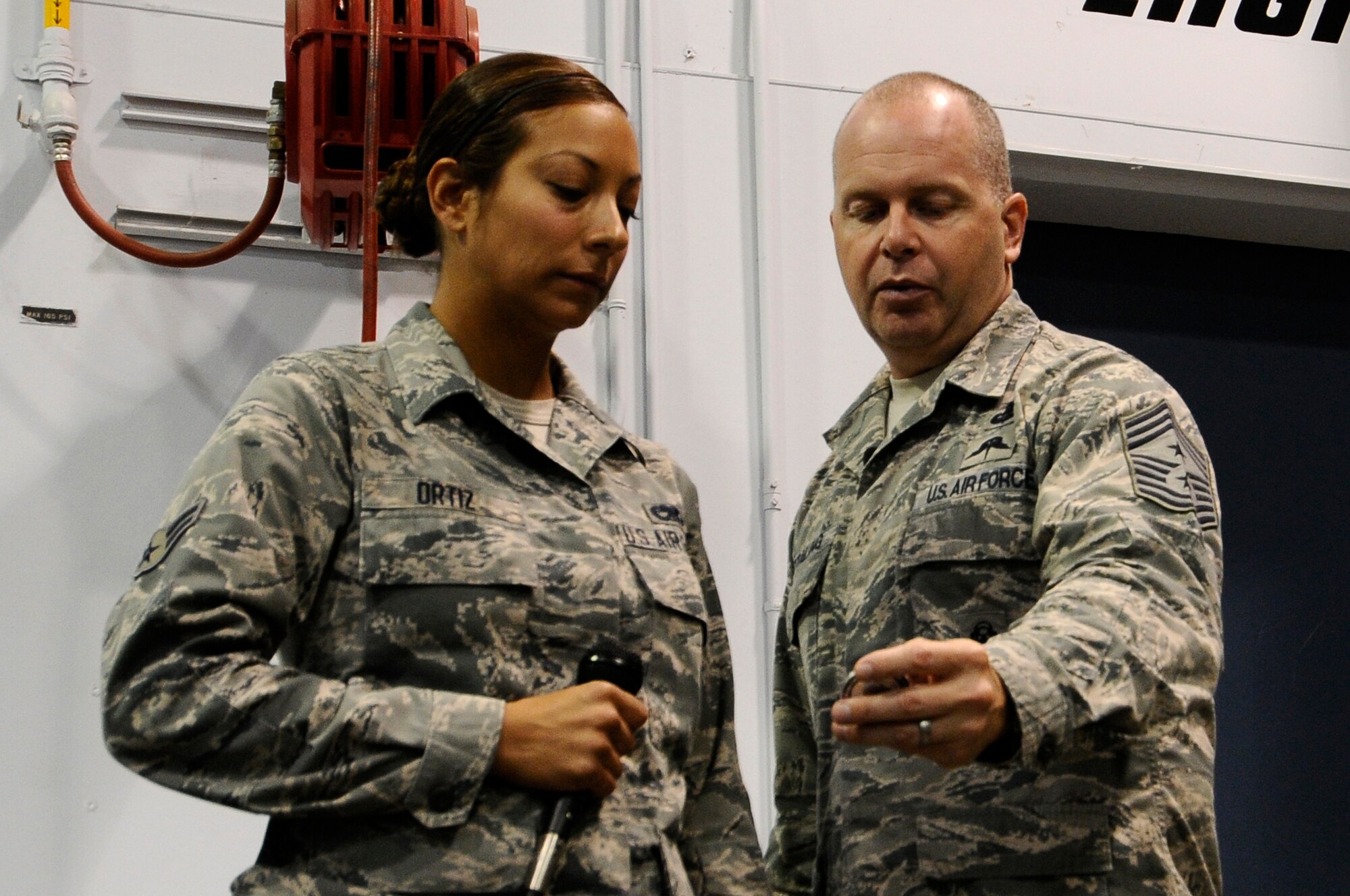 U.S. Air National Guard Command Chief Master Sgt. James W. Hotaling shows Airman 1st Class Amanda Ortiz, 144th Maintenance Group crew chief, his personalized Chief’s Coin during an all call held at the Fresno Air National Guard Base, Calif., July 13, 2014. Ortiz was coined after she answered Chief Hotaling’s three questions correctly.  (U.S. Air National Guard photo by Airman 1st Class Klynne Pearl Serrano/Released)