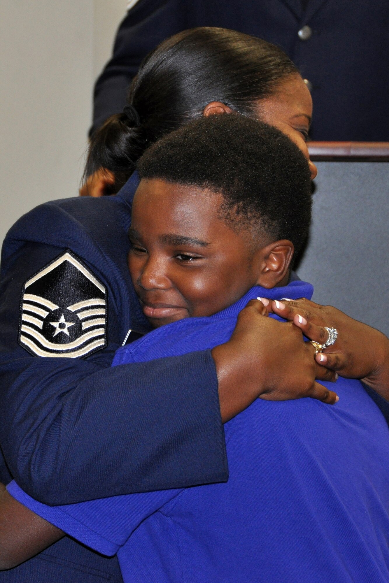 U.S. Air Force Master Sgt. Sabrina Parker hugs her son after presenting all of her children with the "BRAT" coin during her retirement ceremony, July 12, 2014, at Barksdale Air Force Base, La. Parker is retiring from the 307th Logistics Readiness Squadron. (U.S. Air Force photo by Master Sgt. Mary Hinson/Released)