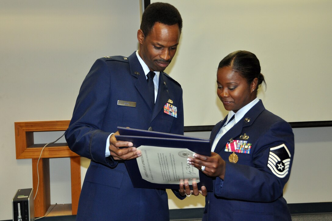 U.S. Air Force Capt. Kennie Neal, 2nd Bomb Wing Chaplain, and Master Sgt. Sabrina Parker read a Certificate of Appreciation during her retirement ceremony, July 12, 2014, at Barksdale Air Force Base, La. Parker is retiring from the 307th Logistics Readiness Squadron. (U.S. Air Force photo by Master Sgt. Mary Hinson/Released)