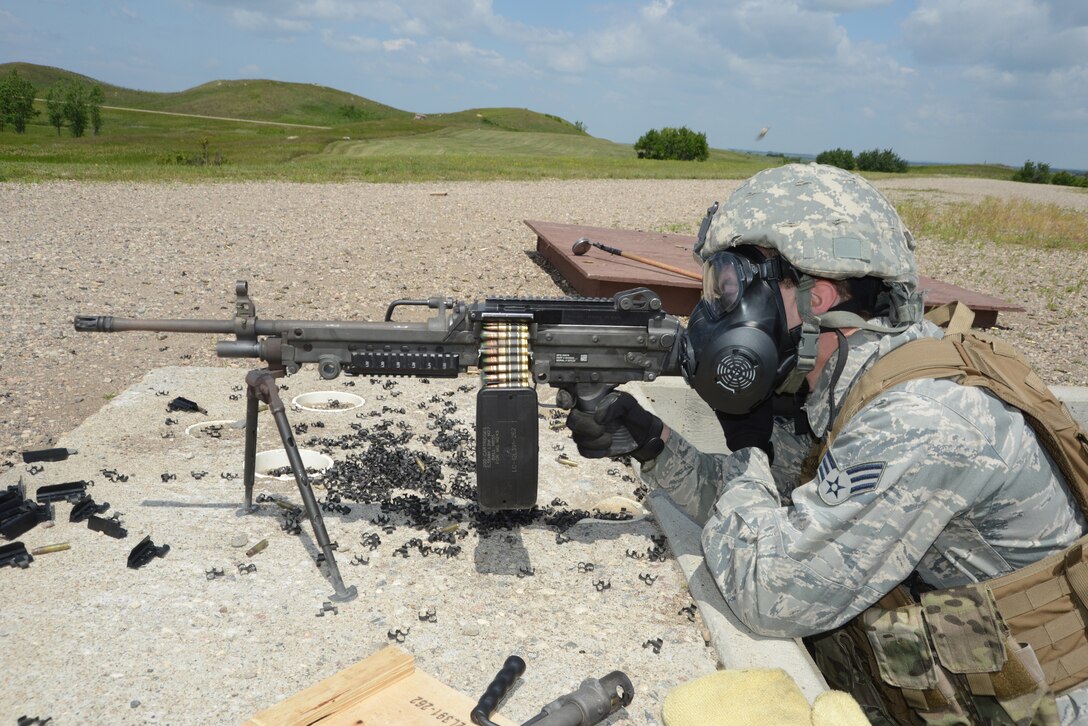 Senior Airman Michael McLaughlin, of the 219th Security Forces Squadron, fires an M249B Light Machine Gun while wearing a gas mask at the firing range at Camp Gilbert C. Grafton, North Dakota, July 15, 2014.  The Airman is performing annual weapons familiarization training and qualification for his assigned mission of missile field security at the Minot Air Force Base, near Minot, North Dakota. (U.S. Air National Guard photo by SMSgt. David H. Lipp/Released)