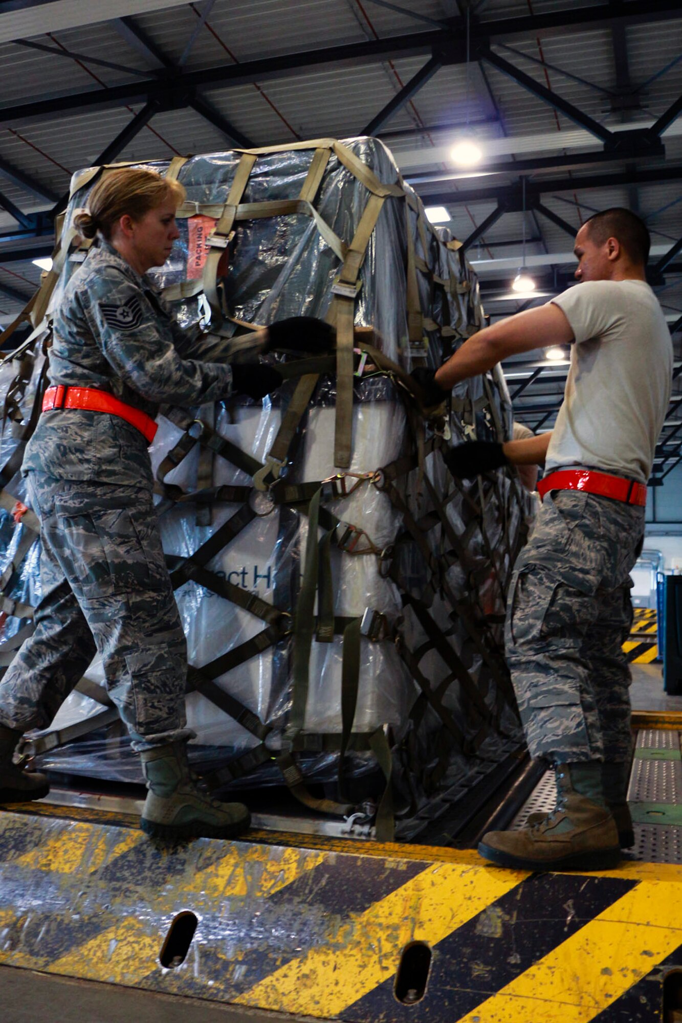 Tech. Sgt. Heather Isaac (left) and Staff Sgt. Wyndell Bagaoisan, 36th Aerial Port Squadron cargo specialists, tighten the netting for a pallet load July 15 at Ramstein Air Base, Germany. These Reservists  from the 446th Airlift Wing at McChord Field, Washington, are participating in an annual training that will allow them to practice and improve their skill sets. (U.S. Air Force Reserve photo by Senior Airman Madelyn McCullough)