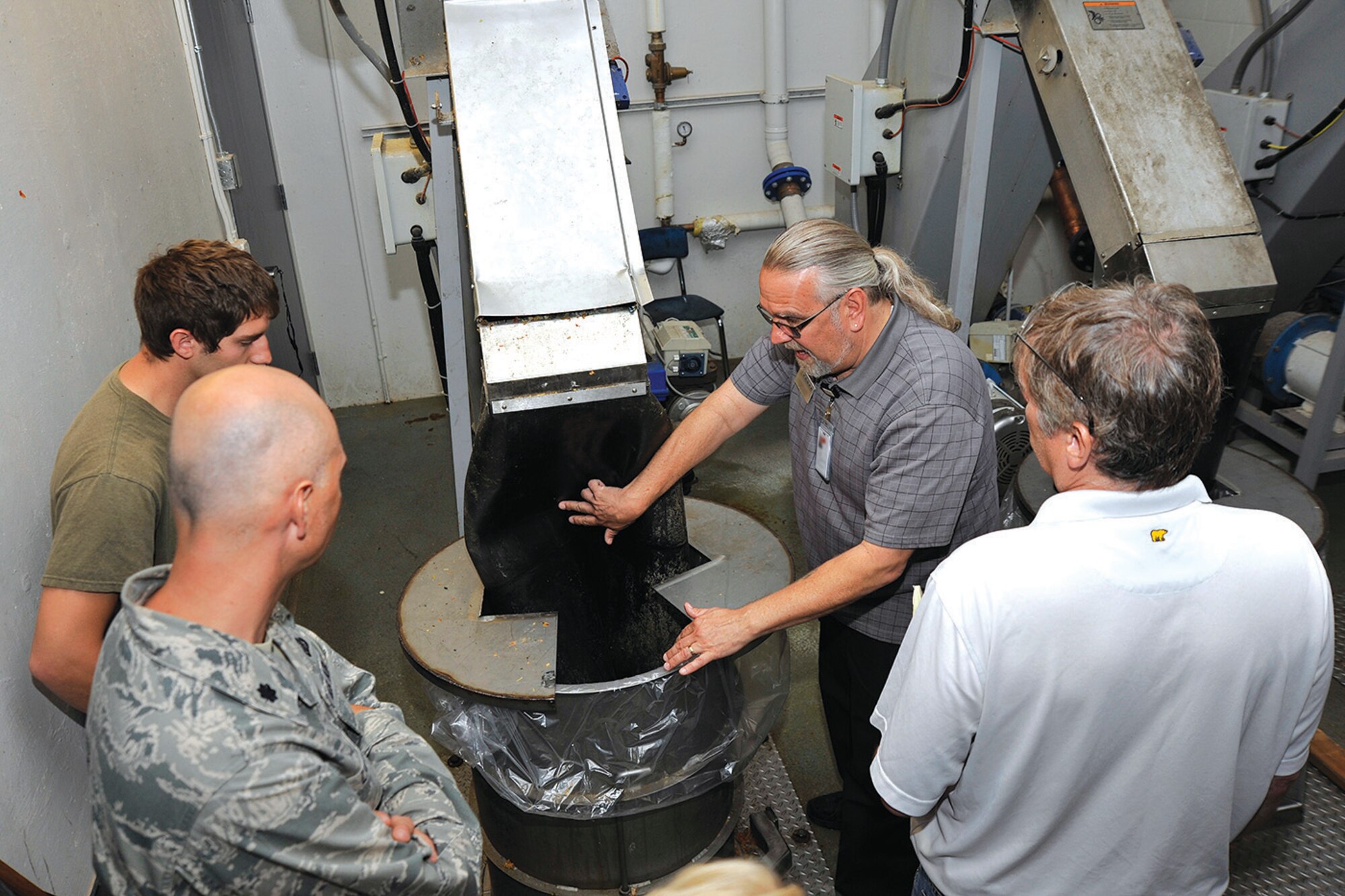 Mitchell Hall facility manager Glen Loyche shows Academy professors how dining hall food waste is converted into pulp at Mitchell Hall Tuesday. (U.S. Air Force photo/Jason Gutierrez)

