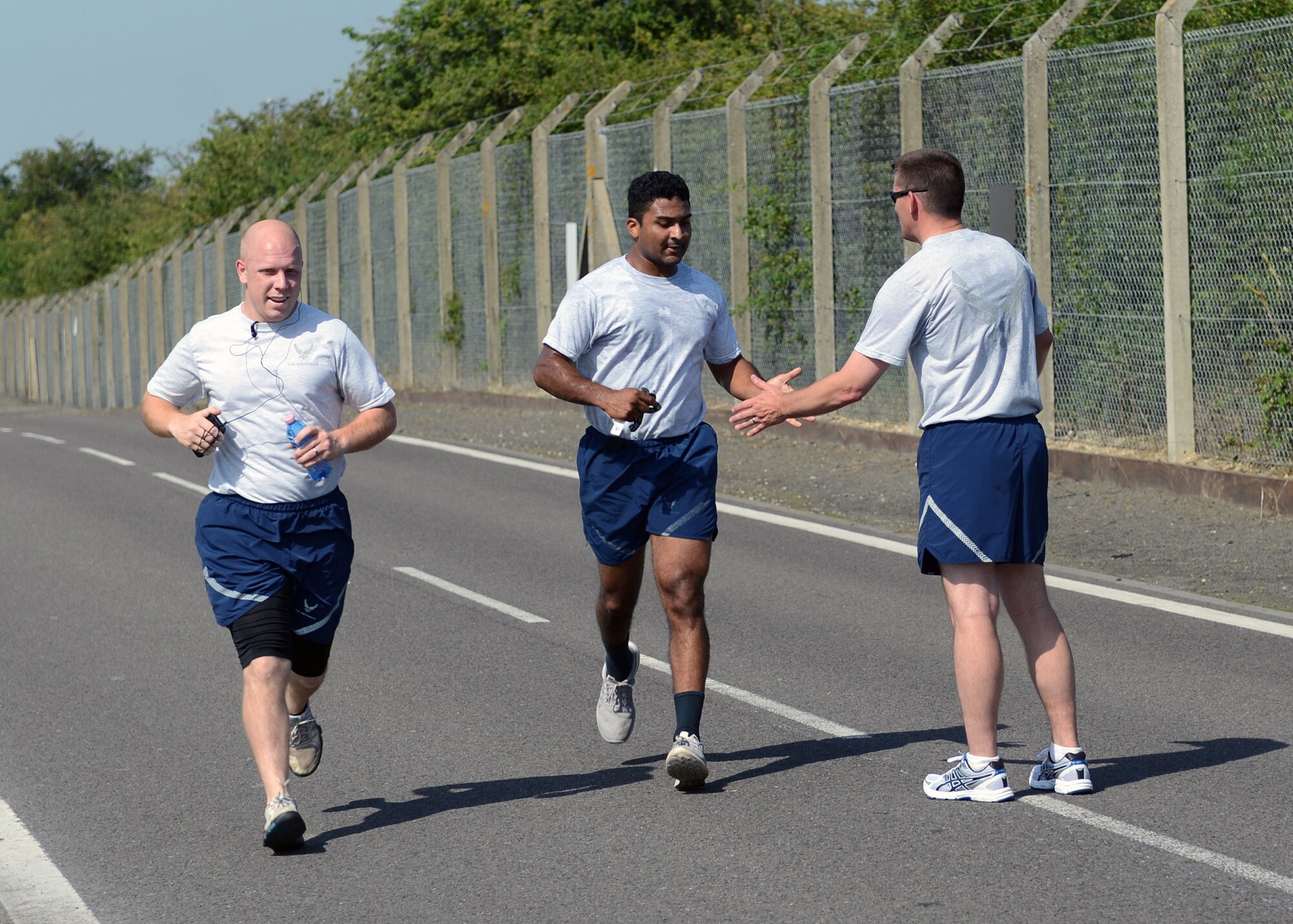 U.S. Air Force Chief Master Sgt. Tracy Jones, right, 100th Air Refueling Wing command chief, high fives Team Mildenhall members as they finish the final straightaway of the monthly 100th Air Refueling Wing 5 km run July 18, 2014, on RAF Mildenhall, England. Each month, Team Mildenhall members gather for exercise and friendly competition. Starting at the Hardstand Fitness Center, participants run along the designated base perimeter route. (U.S. Air Force photo/Airman 1st Class Preston Webb/Released)