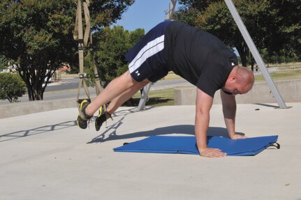 Tech Sgt. James Cummings, 668th Alteration and Installation Squadron NCO in charge of engineering installation, performs pikes using TRX training equipment July 8 at the Gateway Fitness Center, ( Photo by Jose T. Garza III)