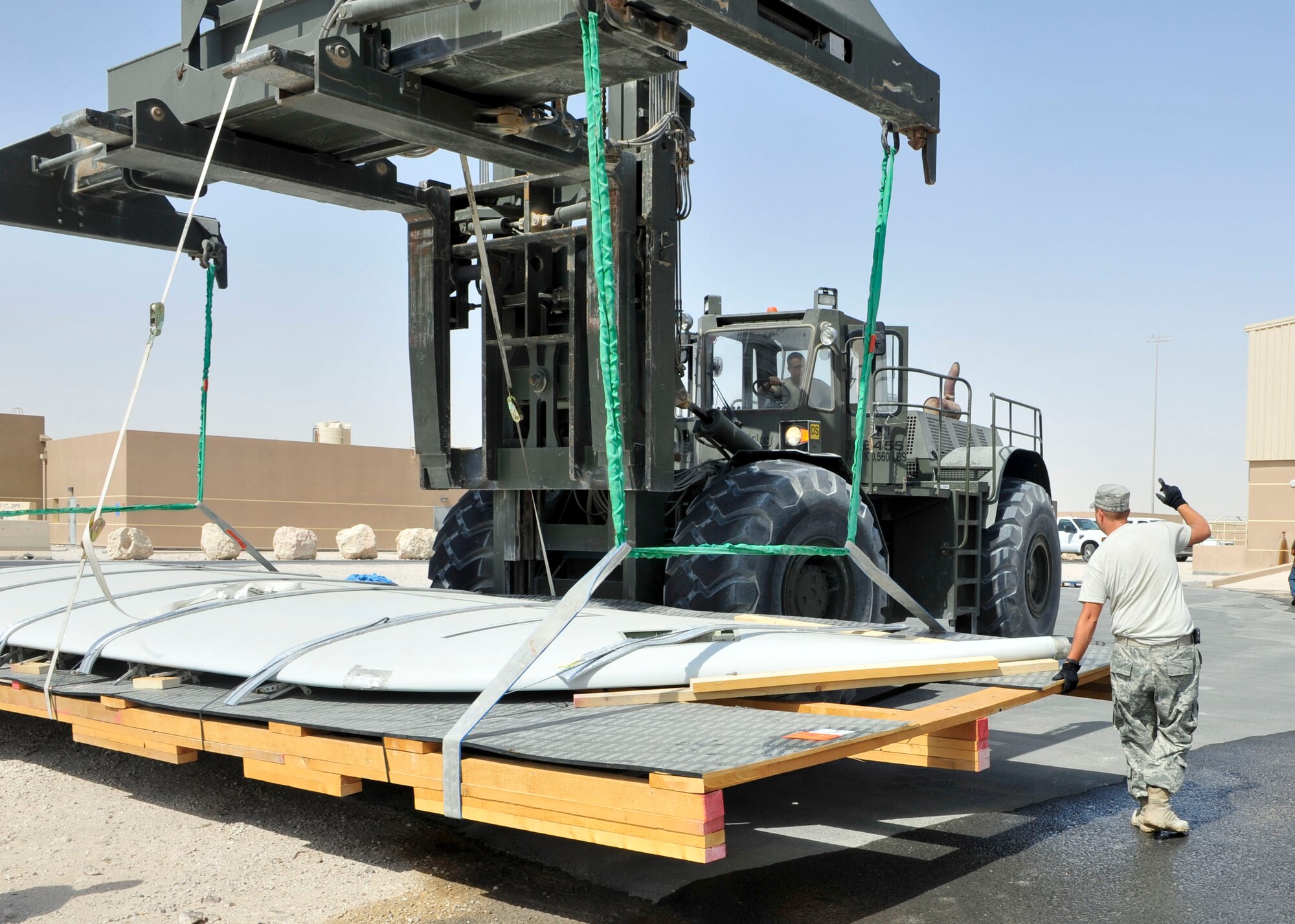 U.S. Air Force Master Sgt. Chad Wallace, 379th Expeditionary Logistics Readiness Squadron Noncommissioned Officer in Charge of training and plans, guides a heavy load operator into place at Al Udeid Air Base, Qatar, July 16, 2014. The project was to move three Joint Surveillance and Target Attack Radar System wings onto trucks, to then be shipped back to the United States for analysis. (U.S. Air Force photo by Senior Airman Colin Cates)