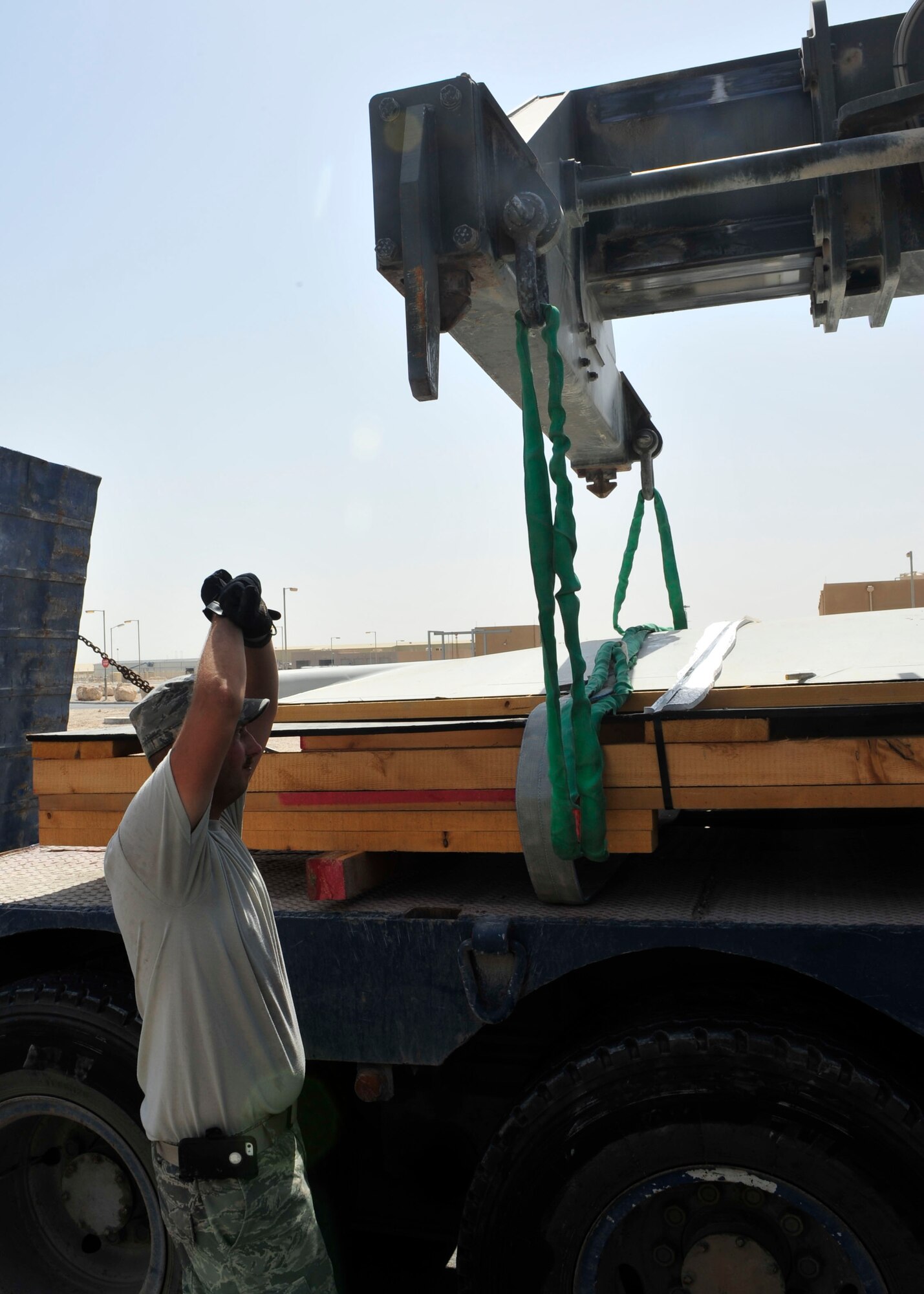 U.S. Air Force Master Sgt. Chad Wallace, 379th Expeditionary Logistics Readiness Squadron Noncommissioned Officer in Charge of training and plans, directs a heavy load operator at Al Udeid Air Base, Qatar, July 16, 2014. The project was to move three Joint Surveillance and Target Attack Radar System wings onto trucks, to then be shipped back to the United States for analysis. (U.S. Air Force photo by Senior Airman Colin Cates)