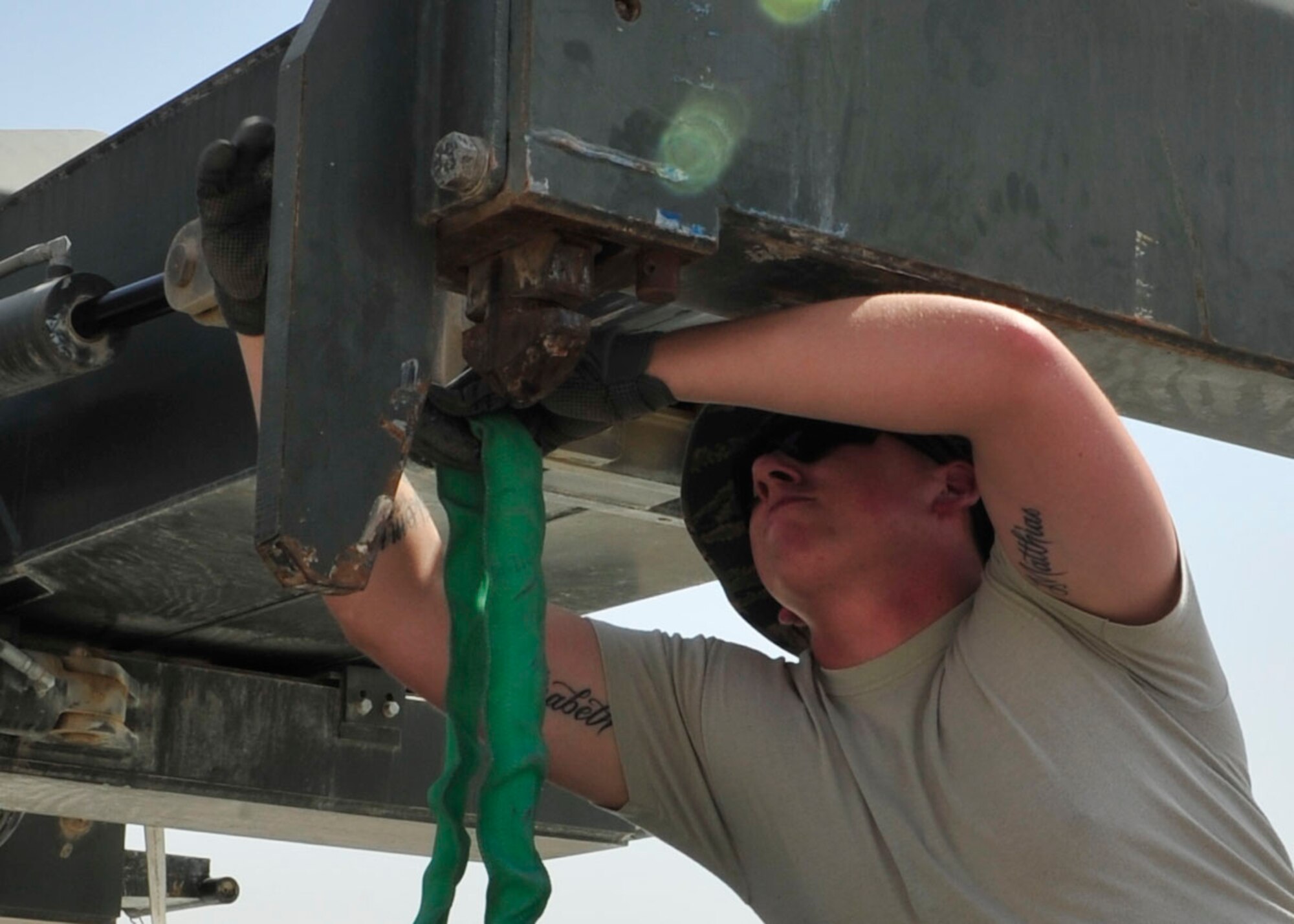 U.S. Air Force Senior Airman Ron Culp, 379th Expeditionary Logistics Readiness Squadron vehicle shop dispatcher, tightens a strap at Al Udeid Air Base, Qatar, July 16, 2014. The process to ship the wings back to the United States started by first building custom pallets for each wing and then securing them for travel. (U.S. Air Force photo by Senior Airman Colin Cates)