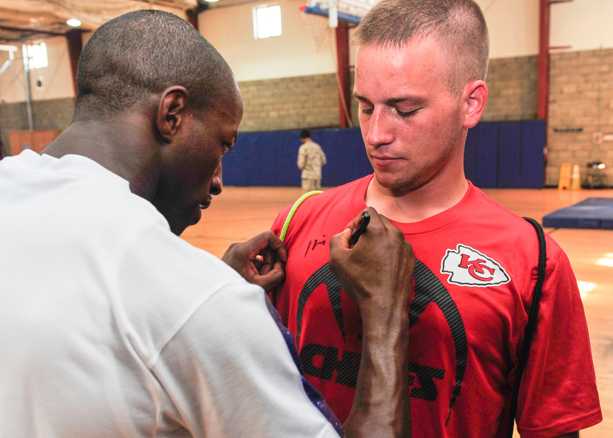National Football League player Husain Abdullah signs the shirt of a Service member during a visit to Al Udeid Air Base, Qatar, July 7, 2014. This was Abdullah’s first visited to Al Udeid Air Base, where he took part in running drills and signing autographs for Service members. Abdullah is a professional football player with the Kansas City Chiefs, where he plays cornerback. (U.S. Air Force photo by Senior Airman Colin Cates)