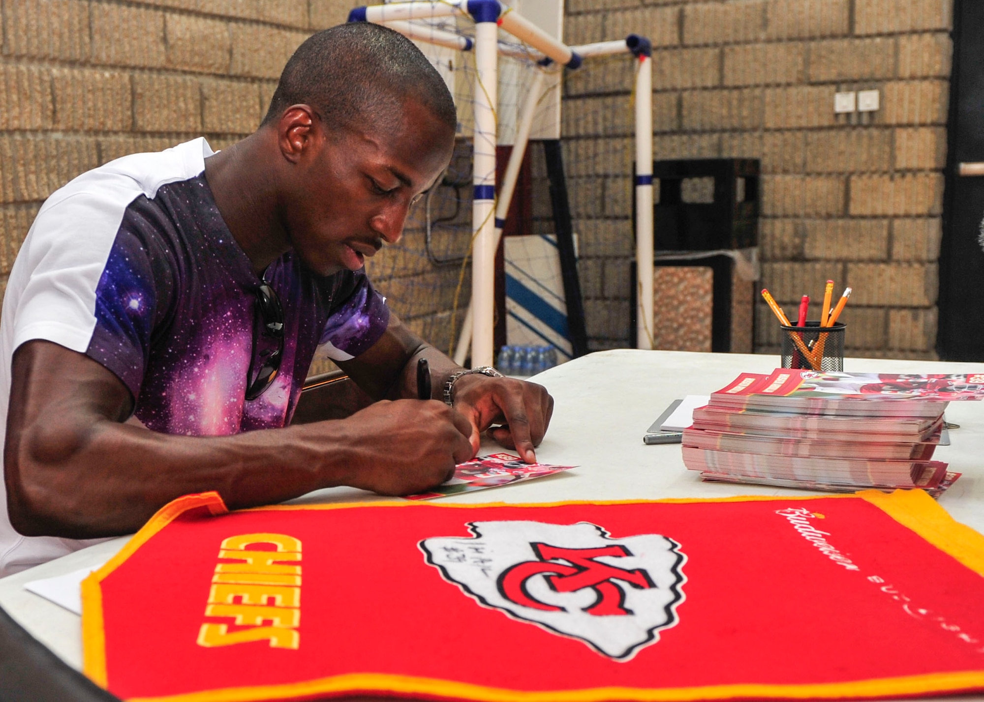 National Football League player Husain Abdullah signs autographs for Service members during a visit to Al Udeid Air Base, Qatar, July 7, 2014.   Abdullah also received a hands-on tour of AUAB as part of his visit and saw how military installations operate. Abdullah is a professional football player with the Kansas City Chiefs, where he plays cornerback. (U.S. Air Force photo by Senior Airman Colin Cates)