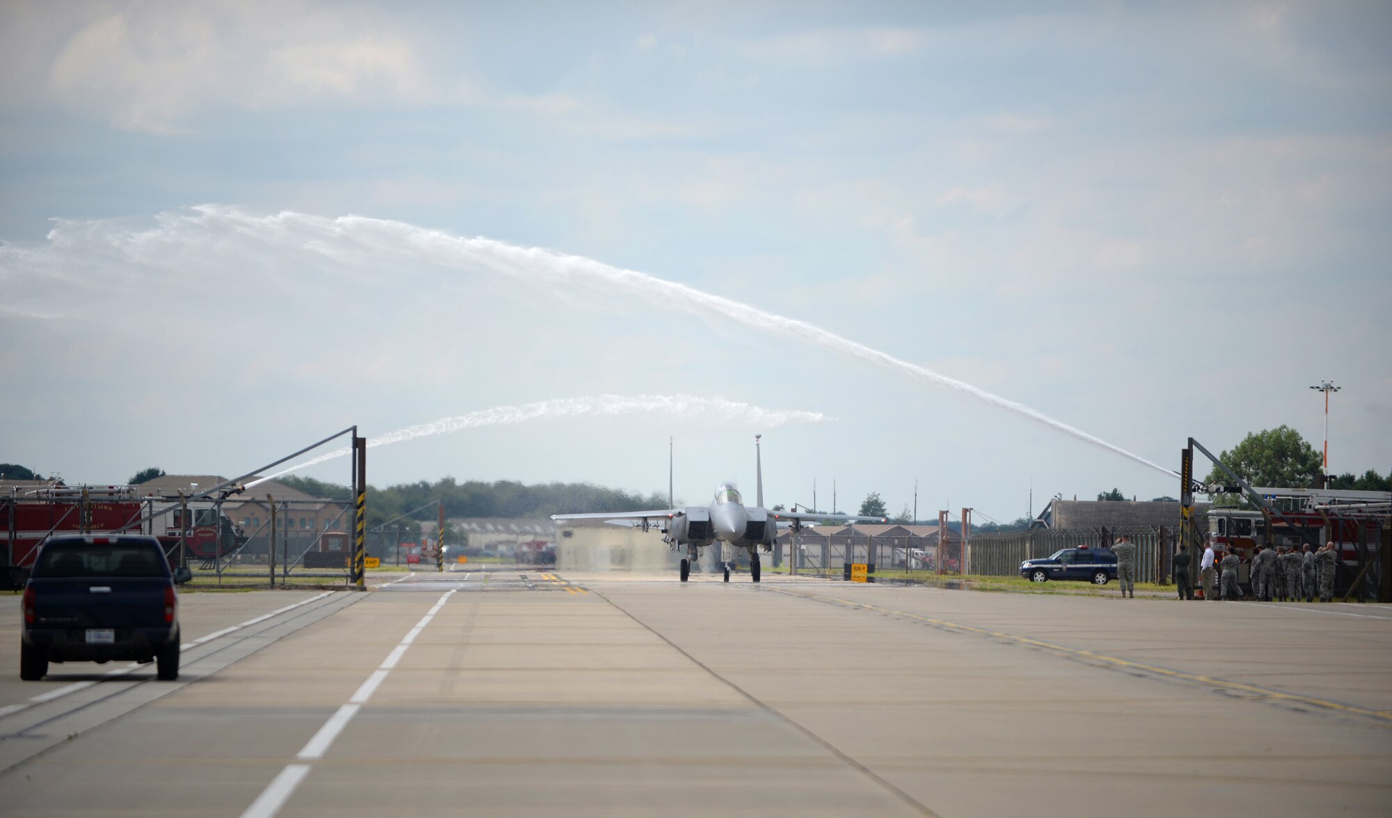 An F-15E Strike Eagle, piloted by Col. Kyle Robinson, 48th Fighter Wing commander, taxies under pressurized water from fire trucks as part of his final flight at Royal Air Force Lakenheath, England, July 17, 2014. Robinson, who has commanded the 48th FW since 2012, was entrusted with the operational readiness, training, morale, welfare, installation support and quality of life of more than 7,000 personnel. (U.S. Air Force photo by Staff Sgt. Emerson Nuñez/Released)